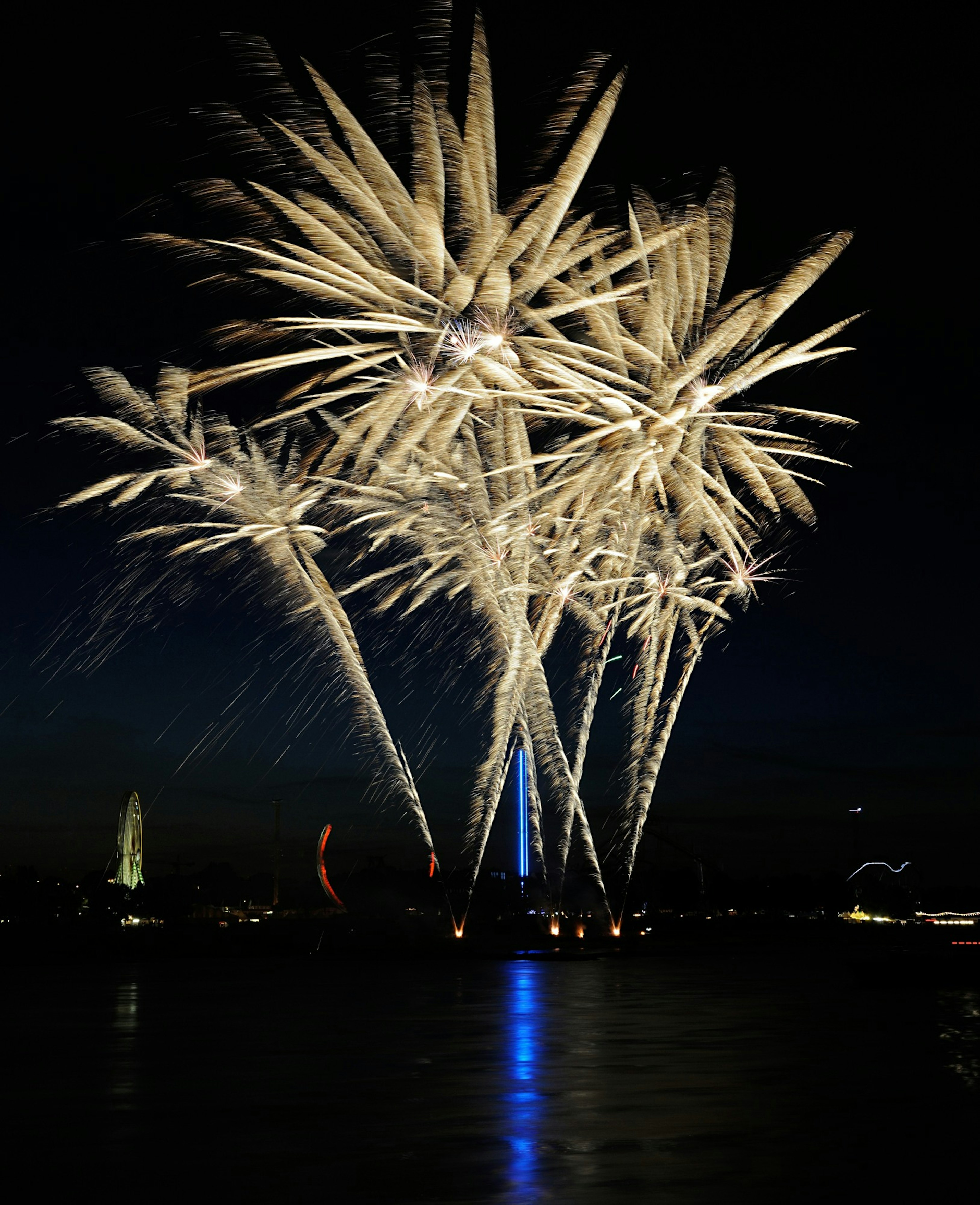 Hermosos fuegos artificiales iluminando el cielo nocturno reflejados en el agua