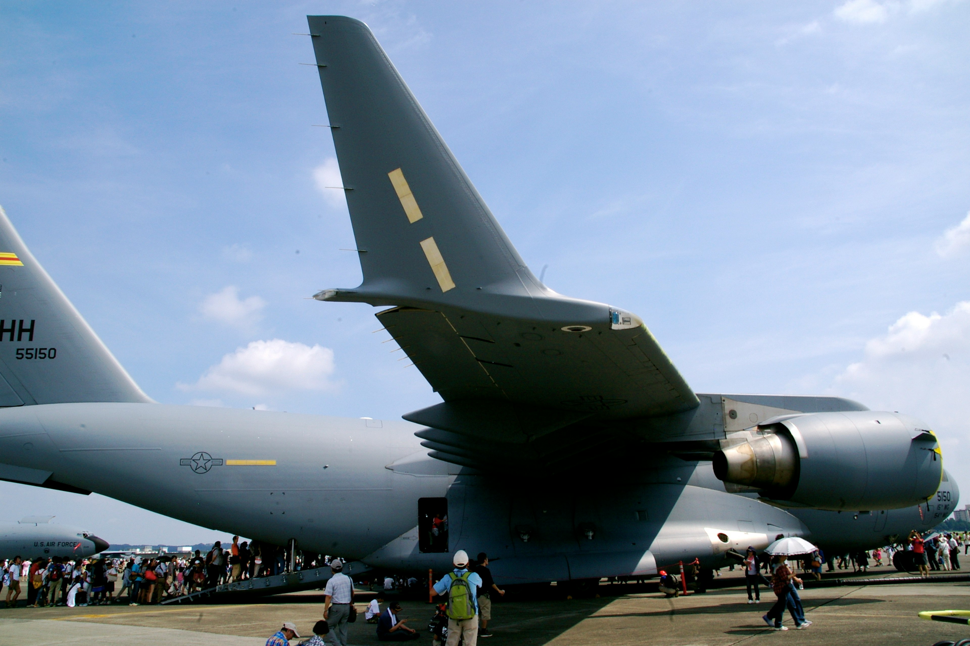 Nahaufnahme eines Militärflugzeugs mit Schwanz und Motor sowie einer Menschenmenge in der Nähe