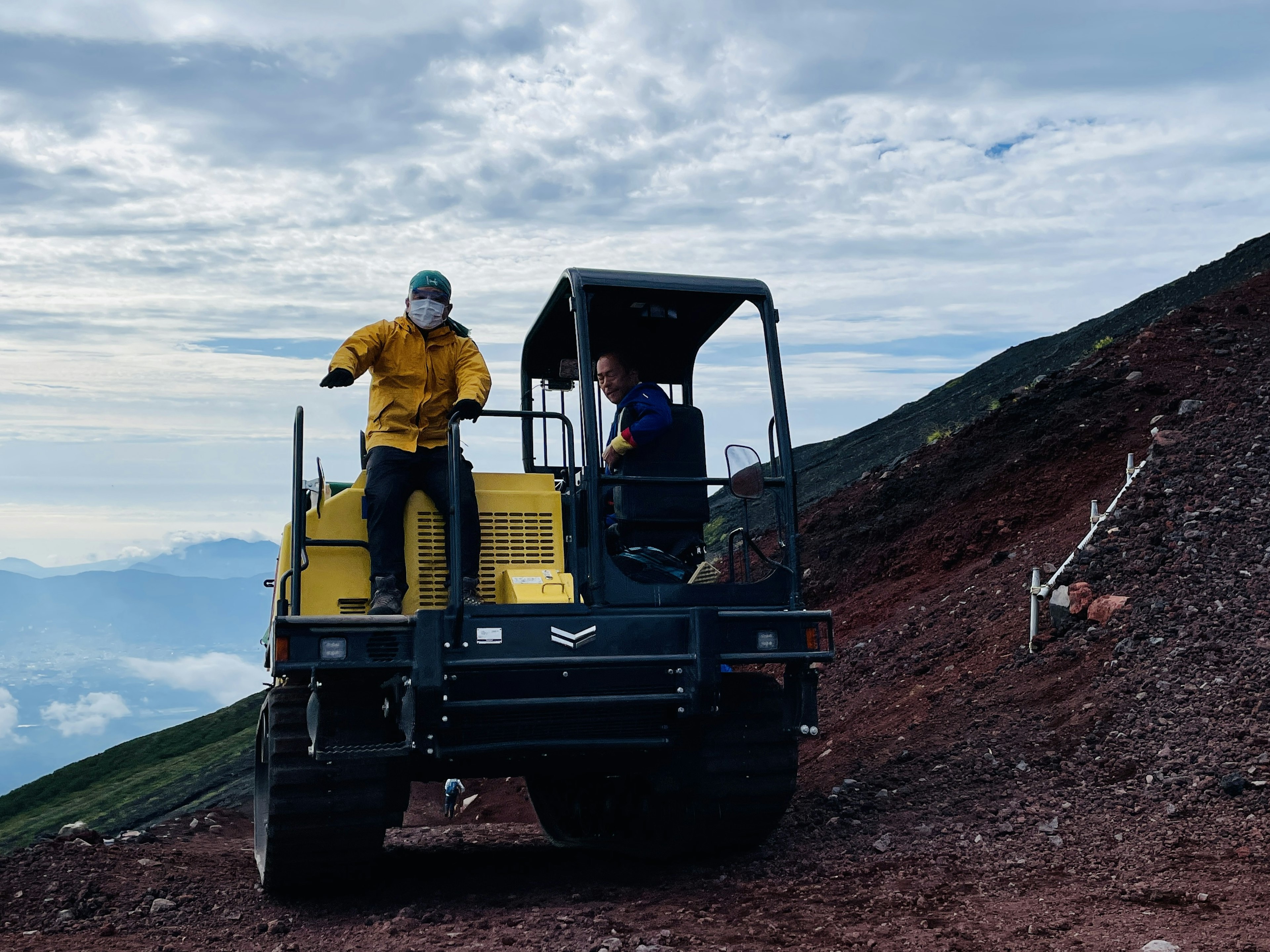 Kendaraan konstruksi di lereng gunung dengan dua pekerja