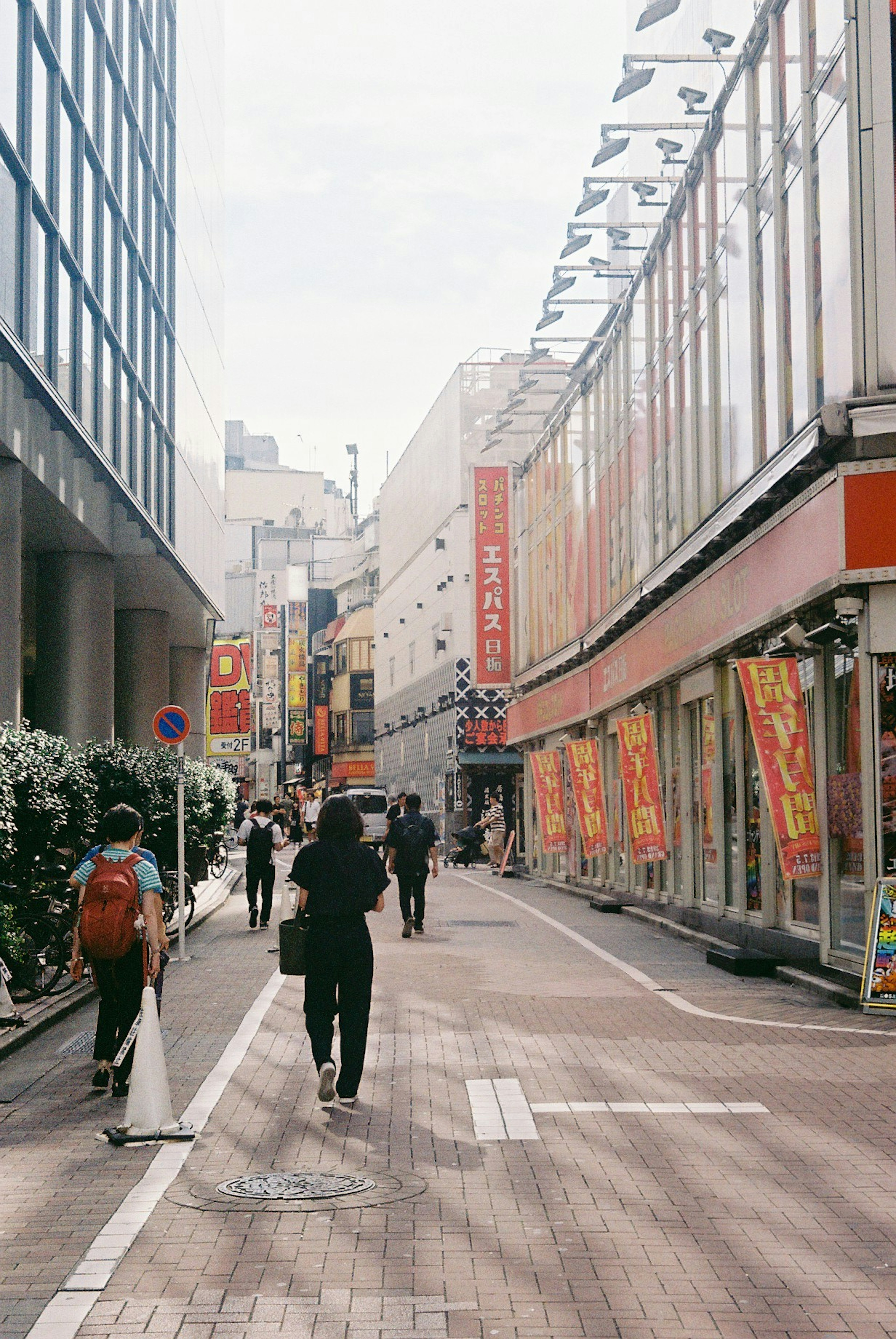 People walking in a busy street in Tokyo with shops and banners