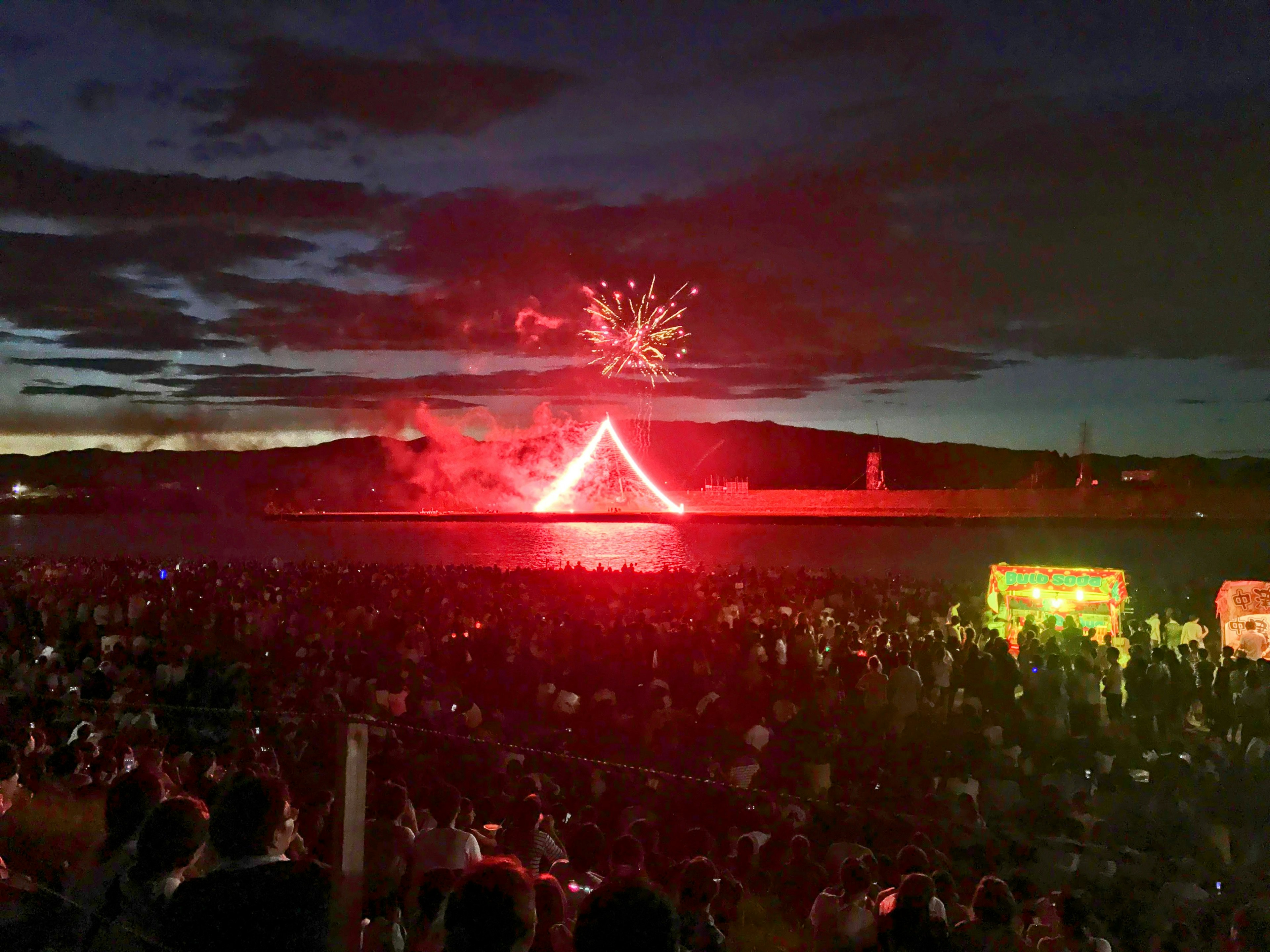 Multitud disfrutando de un espectáculo de fuegos artificiales sobre el agua por la noche