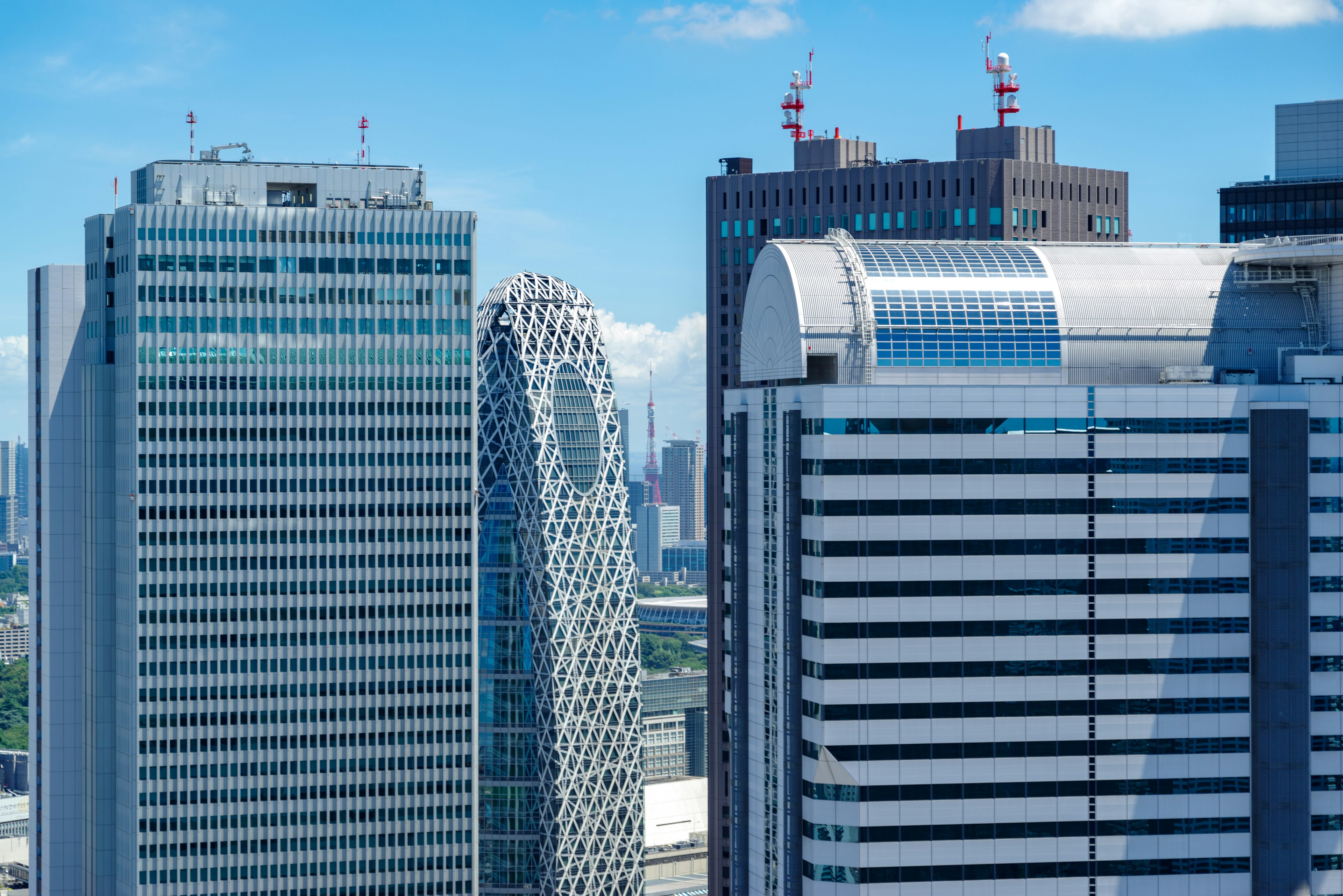 Panoramic view of modern skyscrapers featuring distinctive architectural designs and a clear blue sky