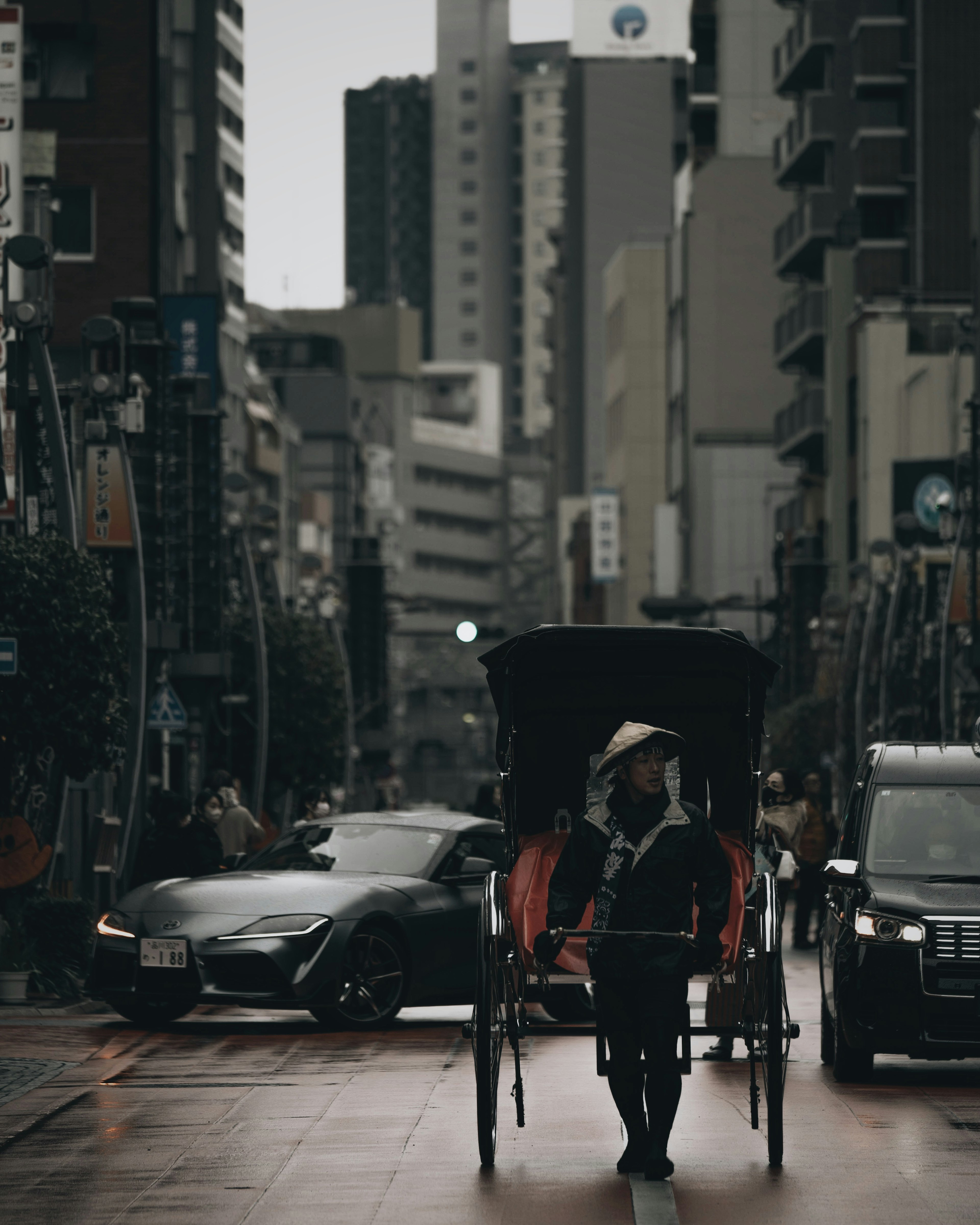 雨の中を走る人力車と現代的なビル群の風景