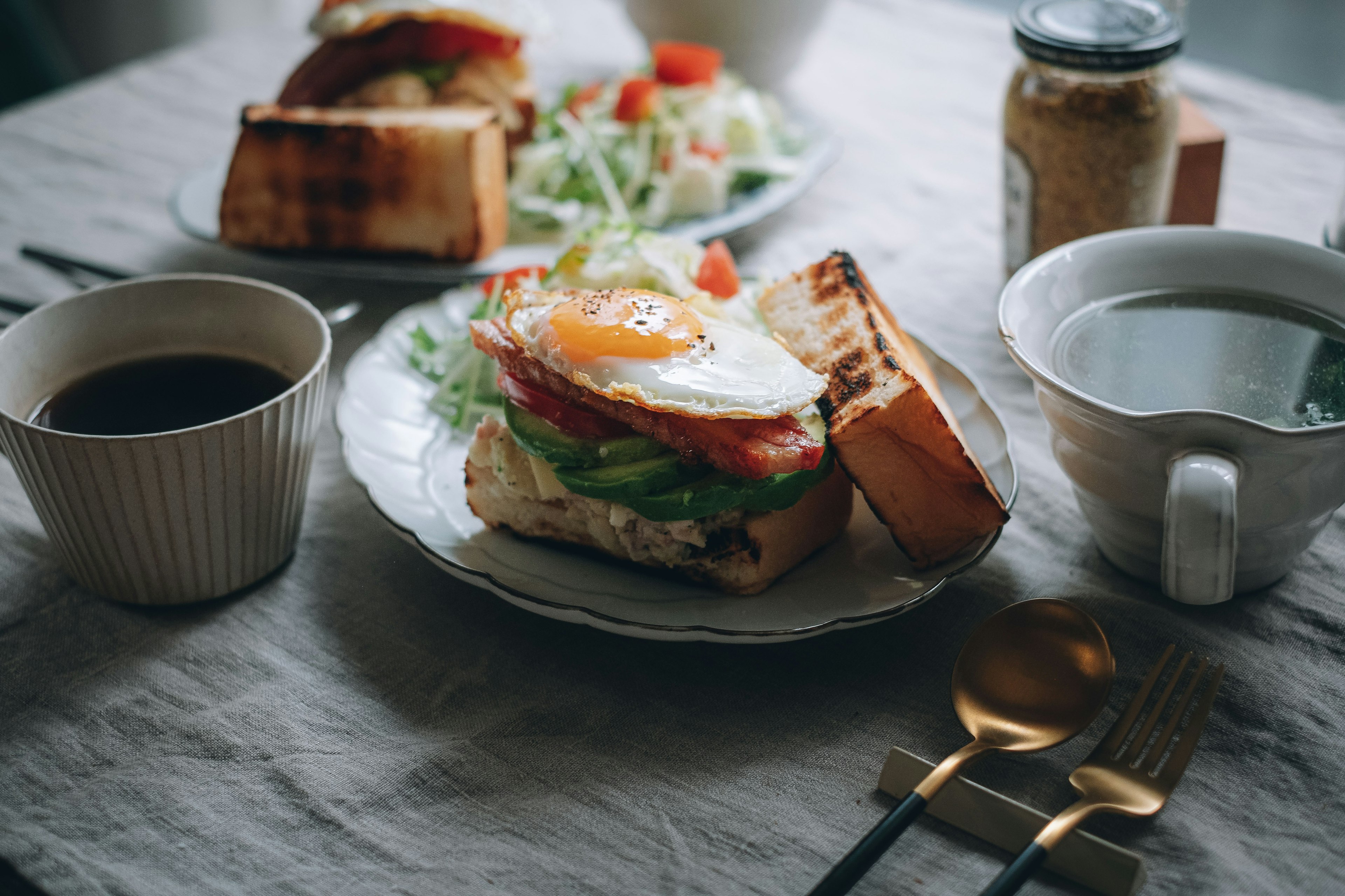 Piring sarapan dengan sandwich telur dan sayuran kopi dan salad di atas meja