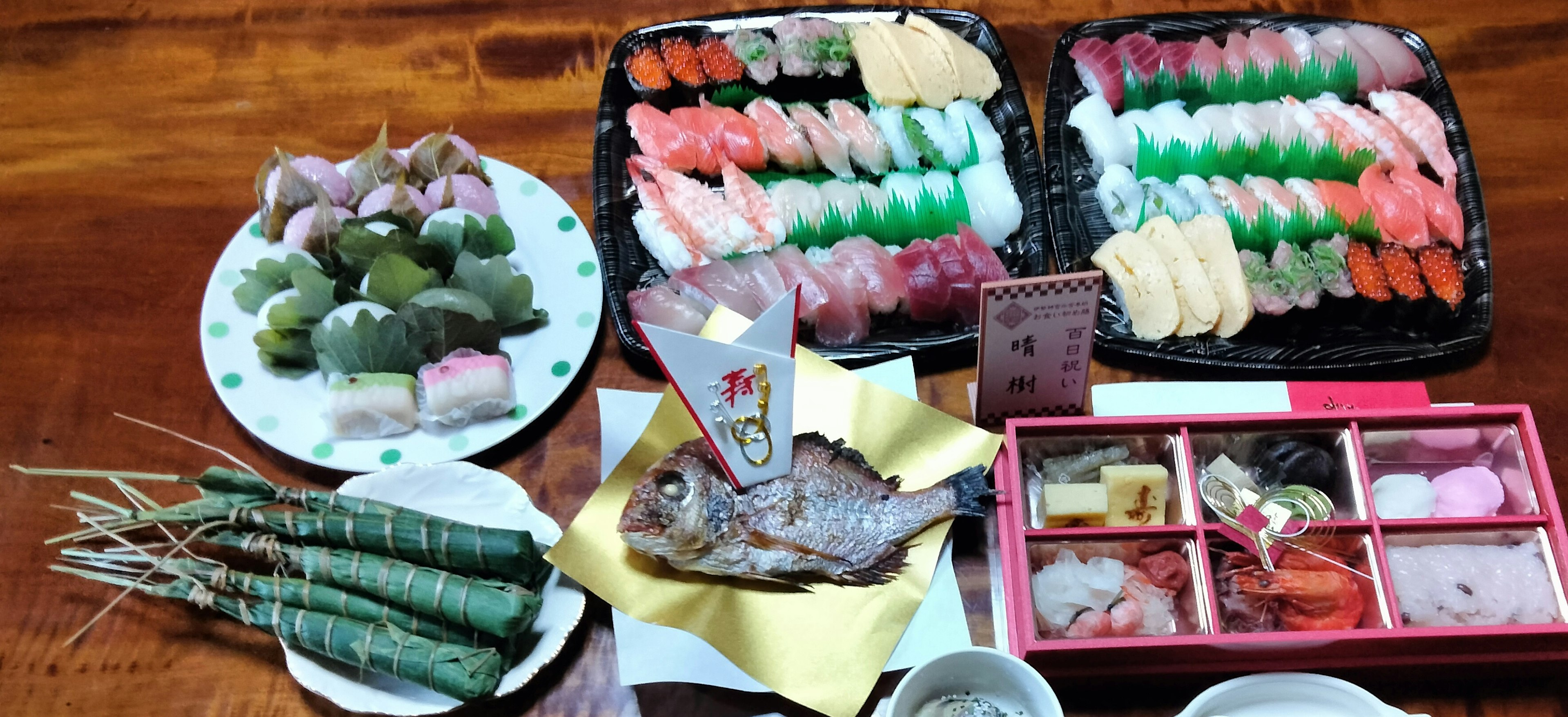 Colorido surtido de sushi y wagashi con una dorada entera a la parrilla y platos envueltos en hojas de bambú