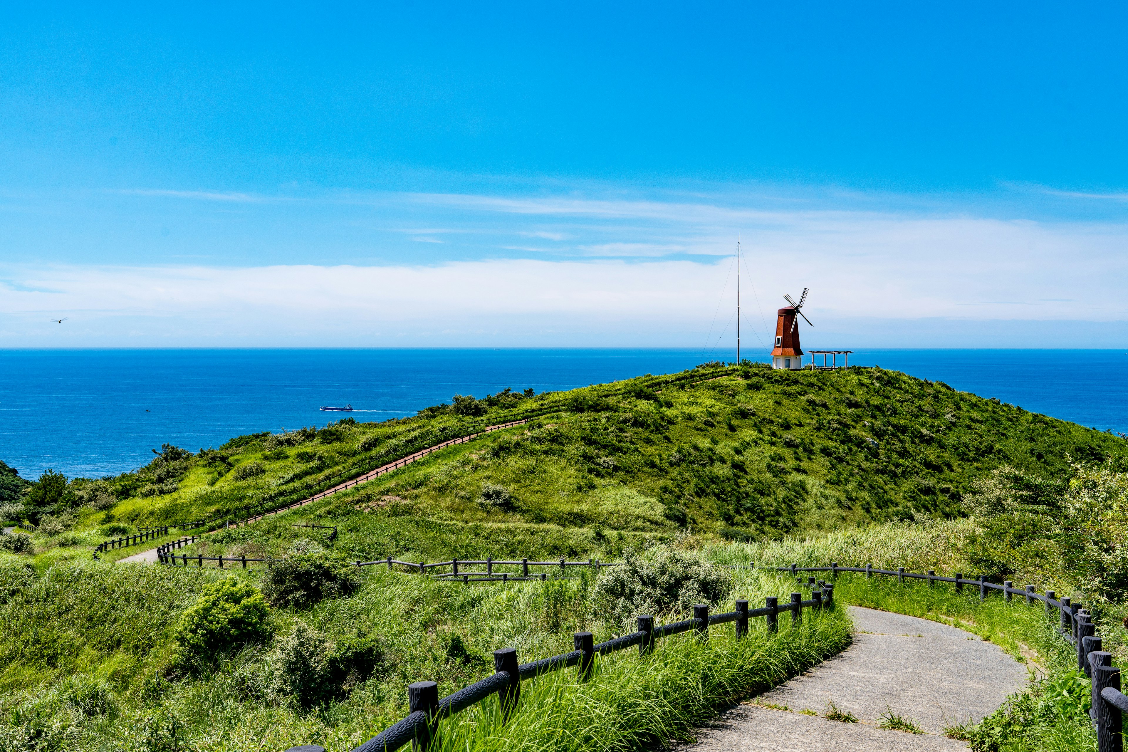 Statua su una collina che sovrasta l'oceano blu e il cielo con vegetazione lussureggiante