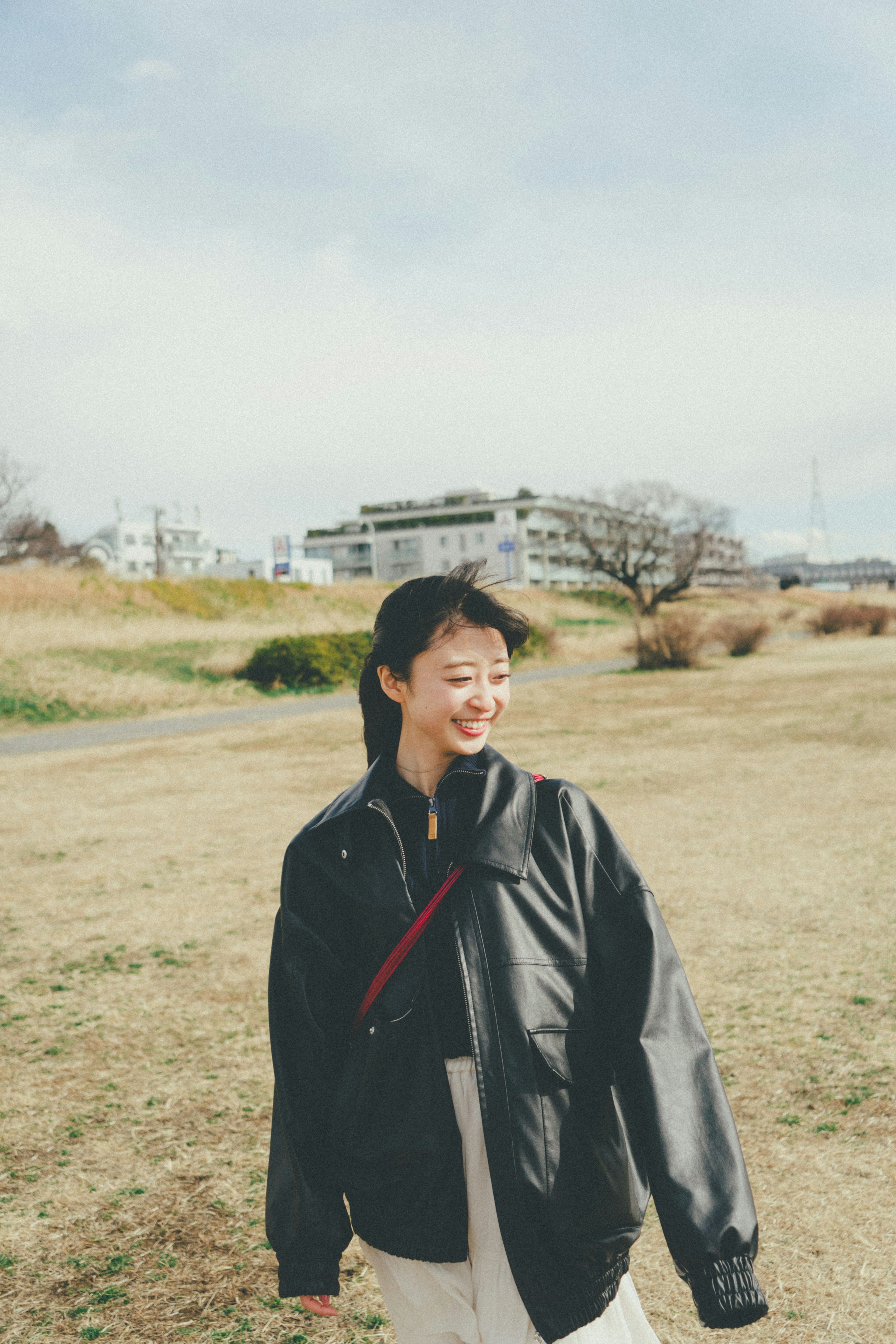 公園で黒いジャケットを着た女性が微笑んでいる