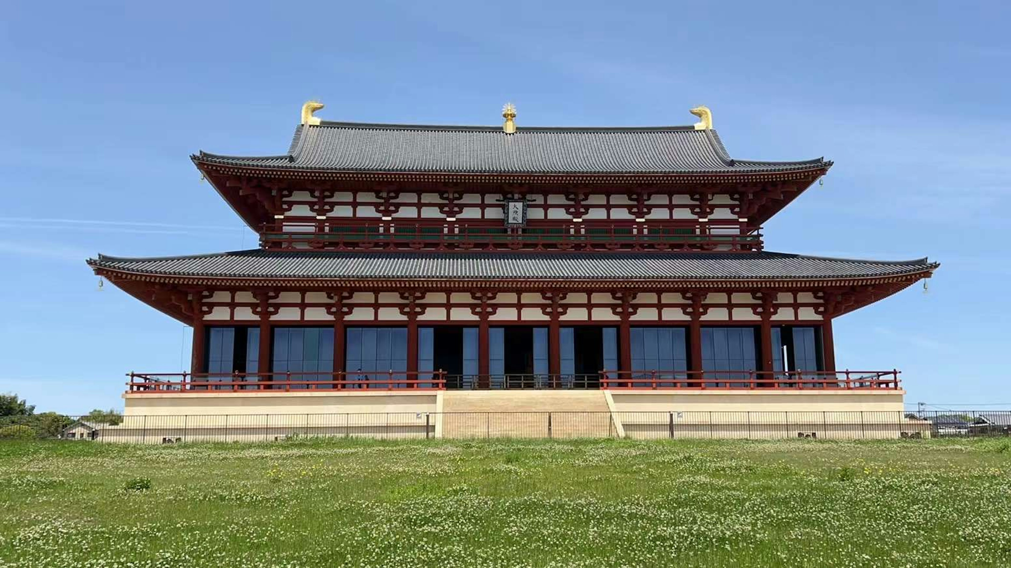 Traditional temple building under a clear blue sky featuring a large roof and decorative design