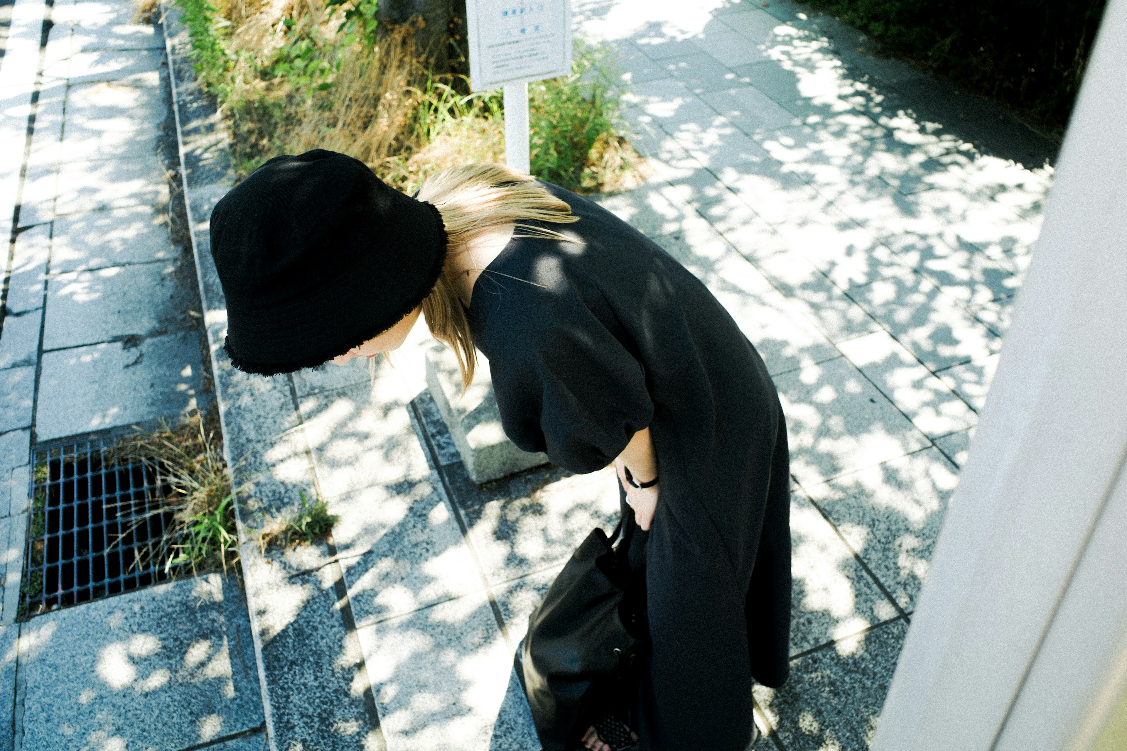 Une femme avec un chapeau noir regardant le sol