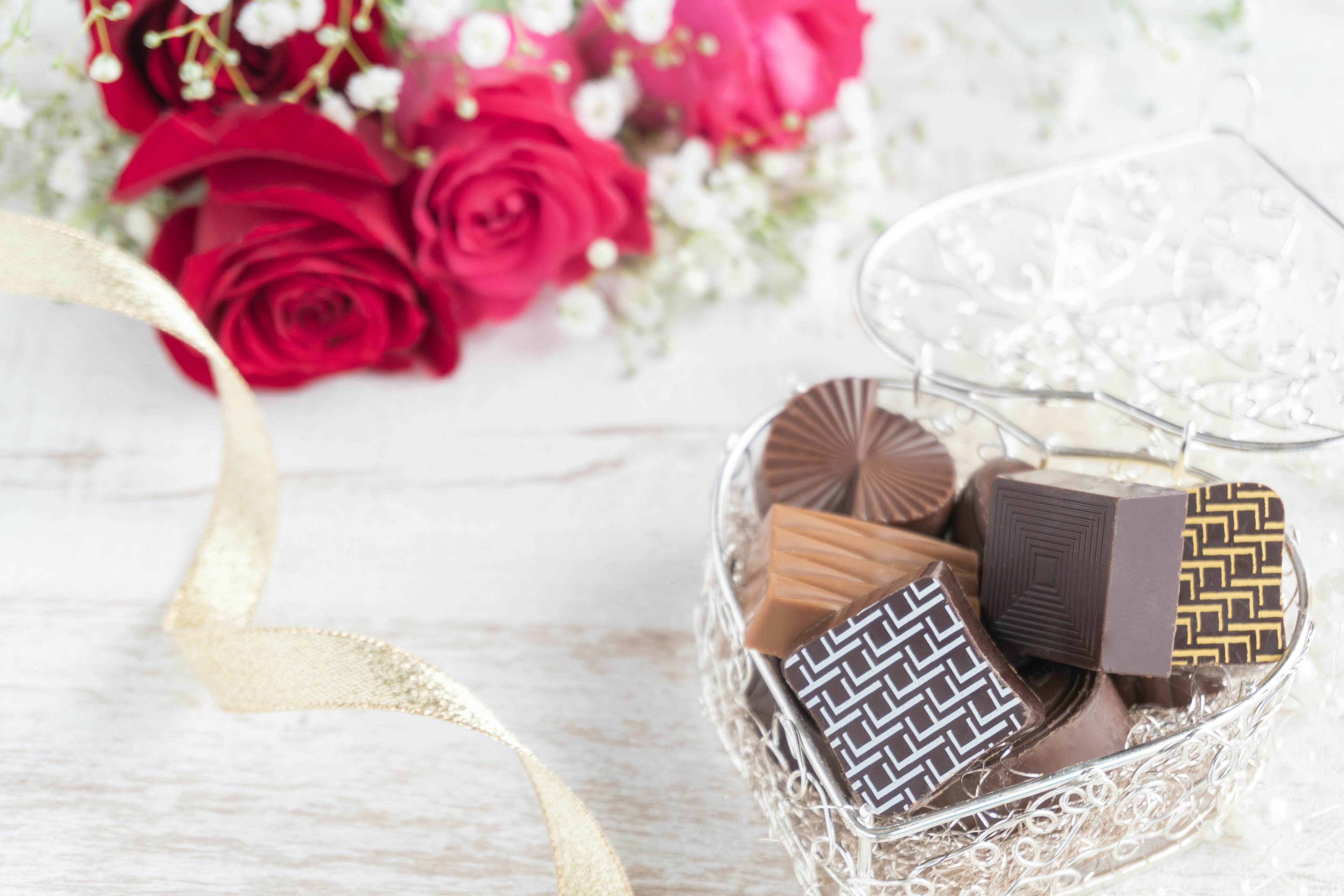 Caja en forma de corazón llena de chocolates y un ramo de rosas rojas