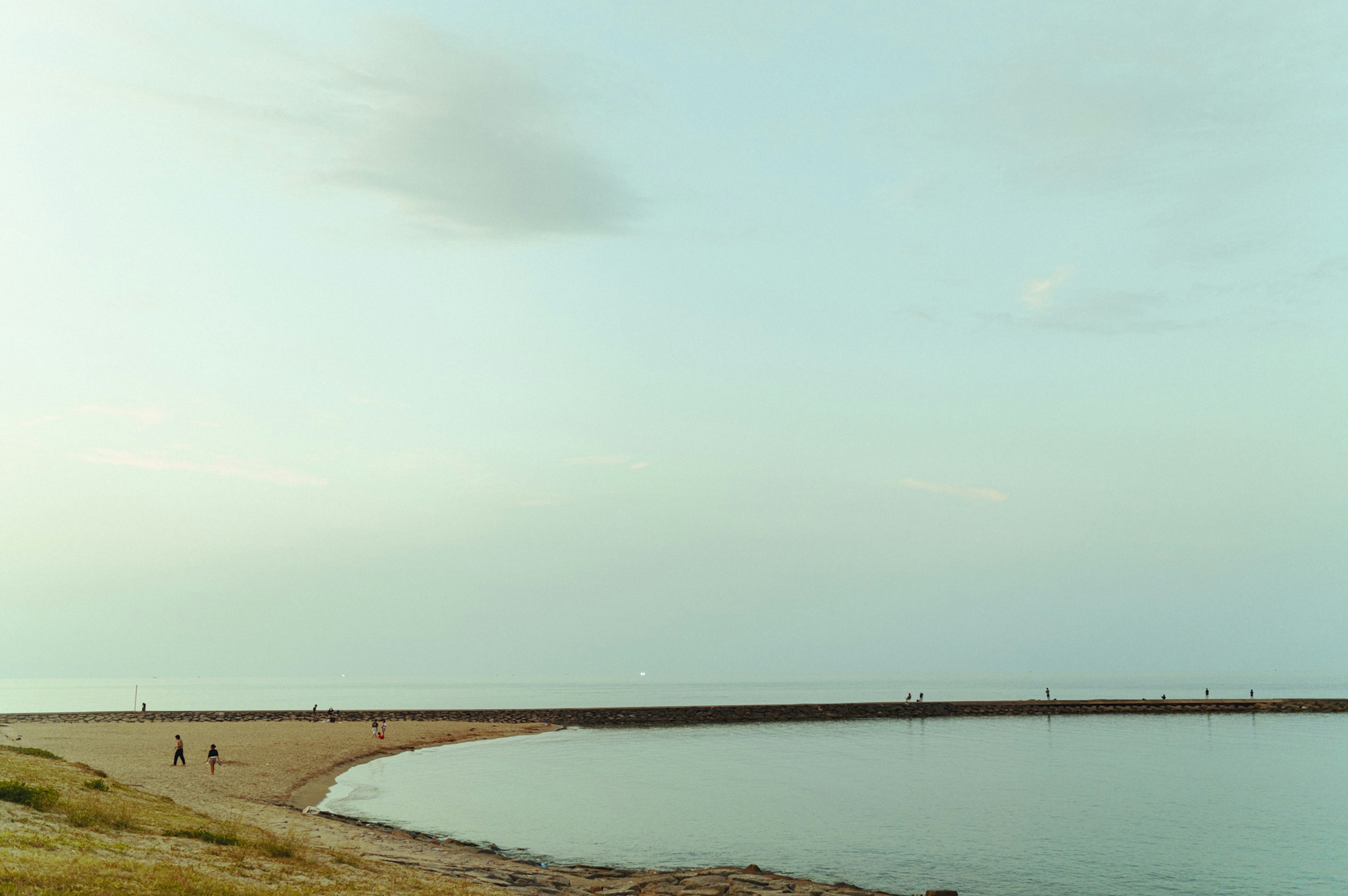 Serene coastline with calm water and distant figures