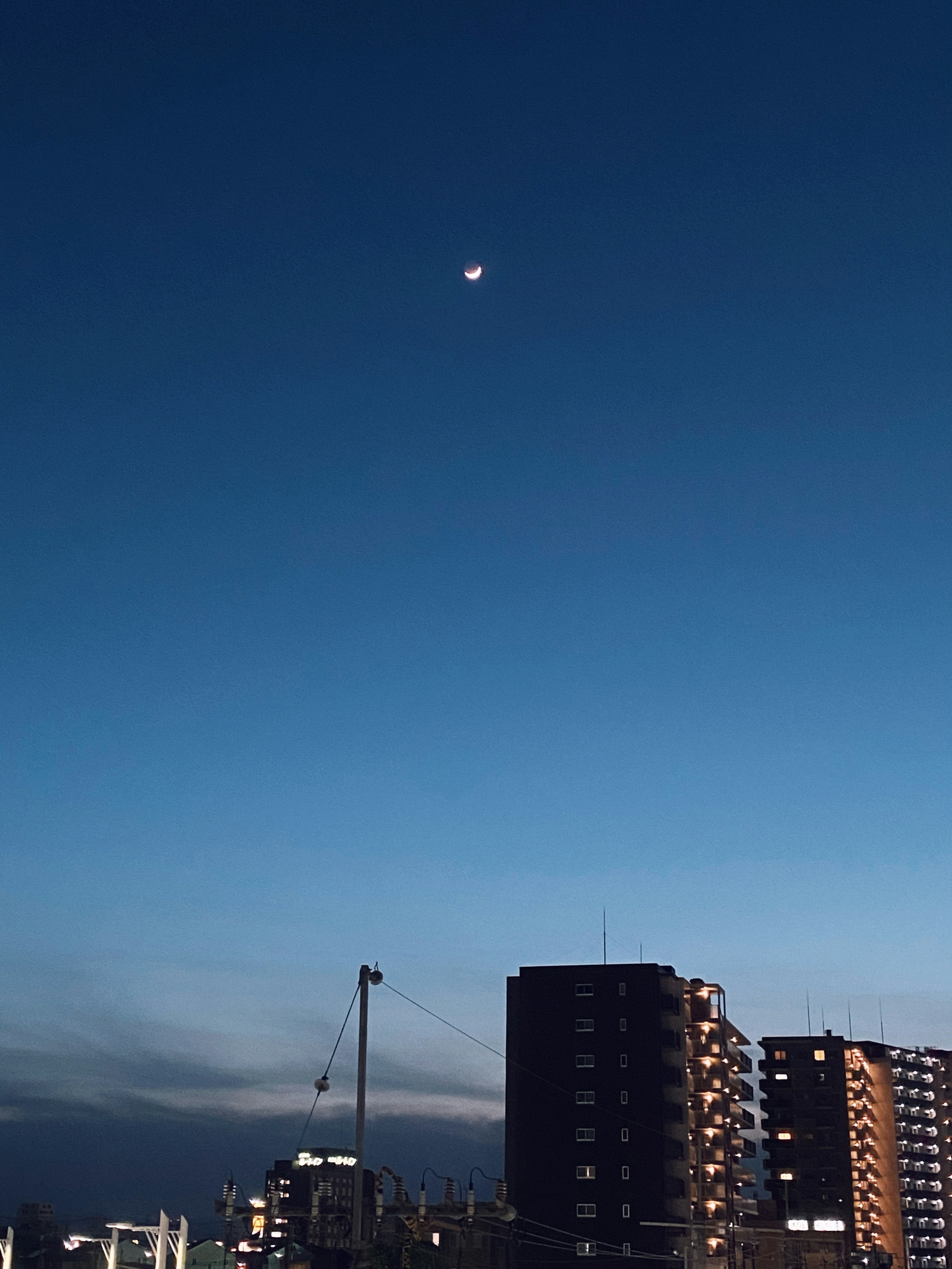 Bulan di langit biru dengan siluet kota