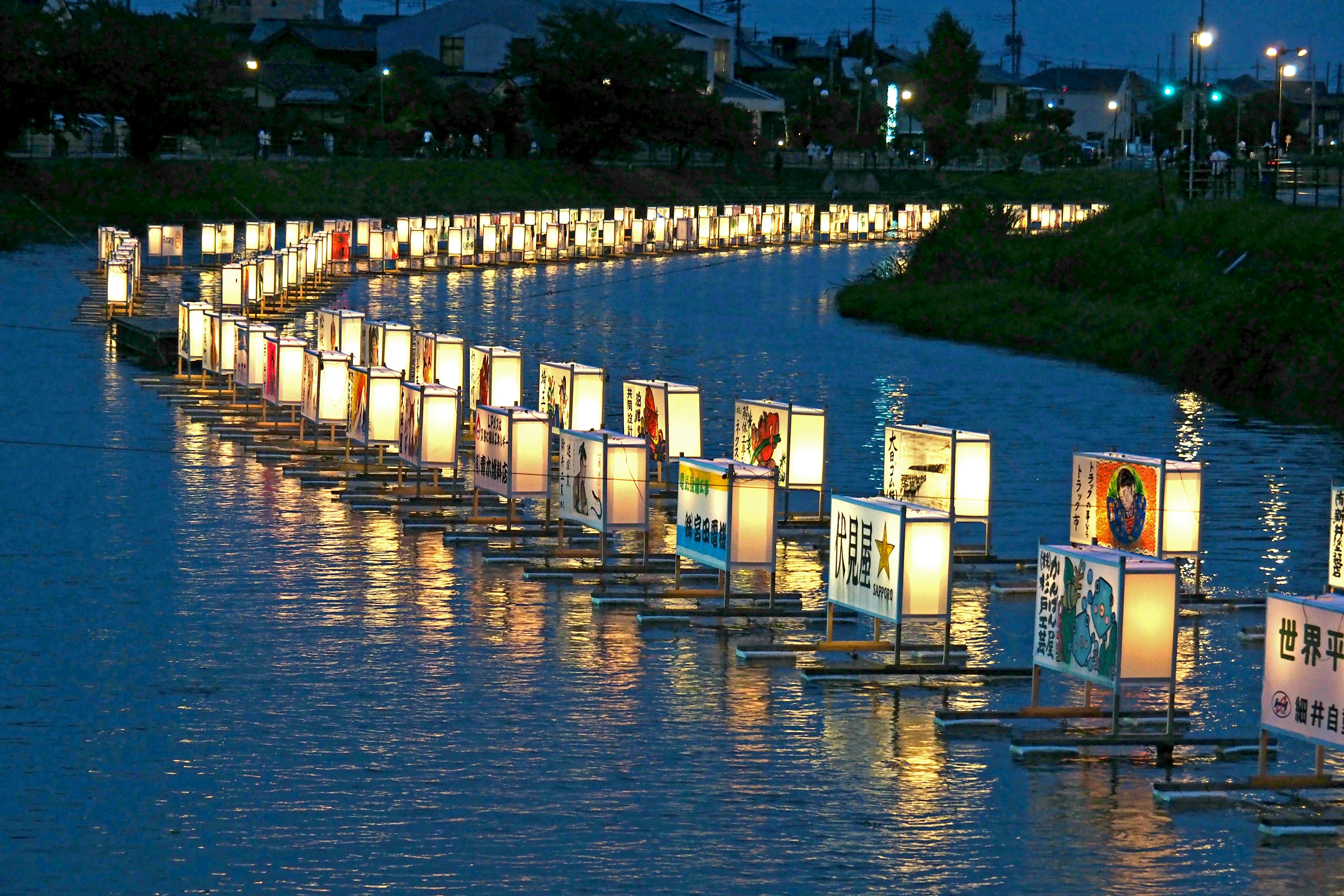 Una serena esposizione di lanterne galleggianti su un fiume di notte con riflessi