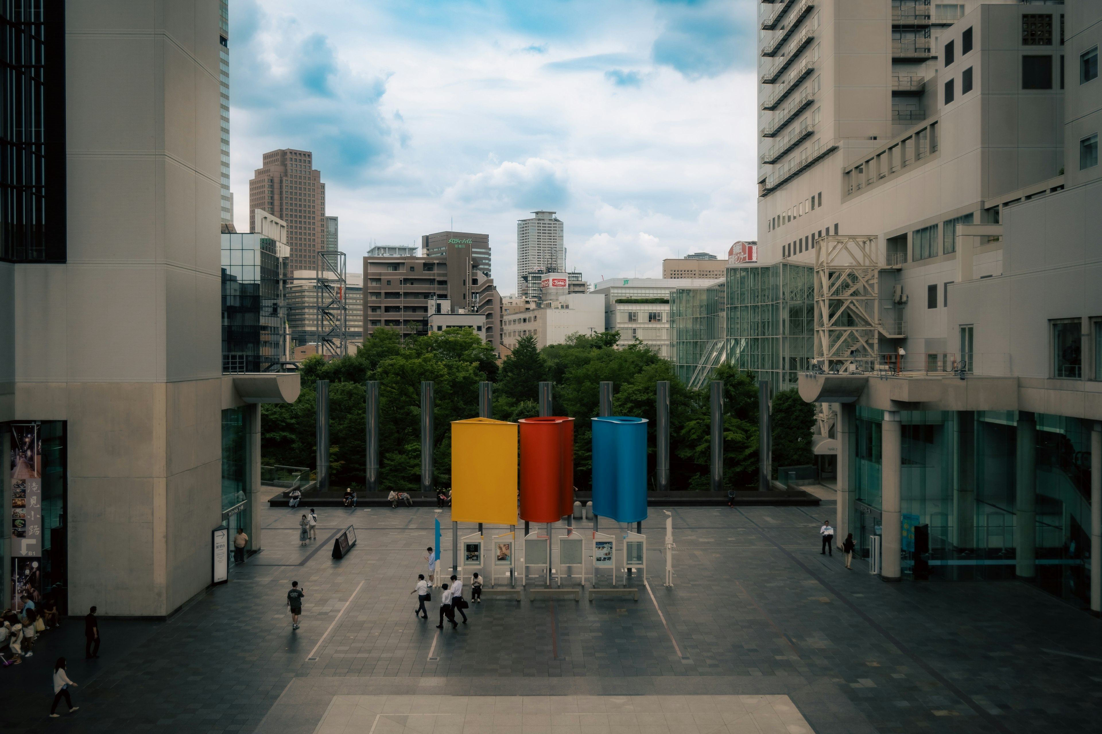 Colorful cylindrical sculptures in an urban landscape with surrounding buildings