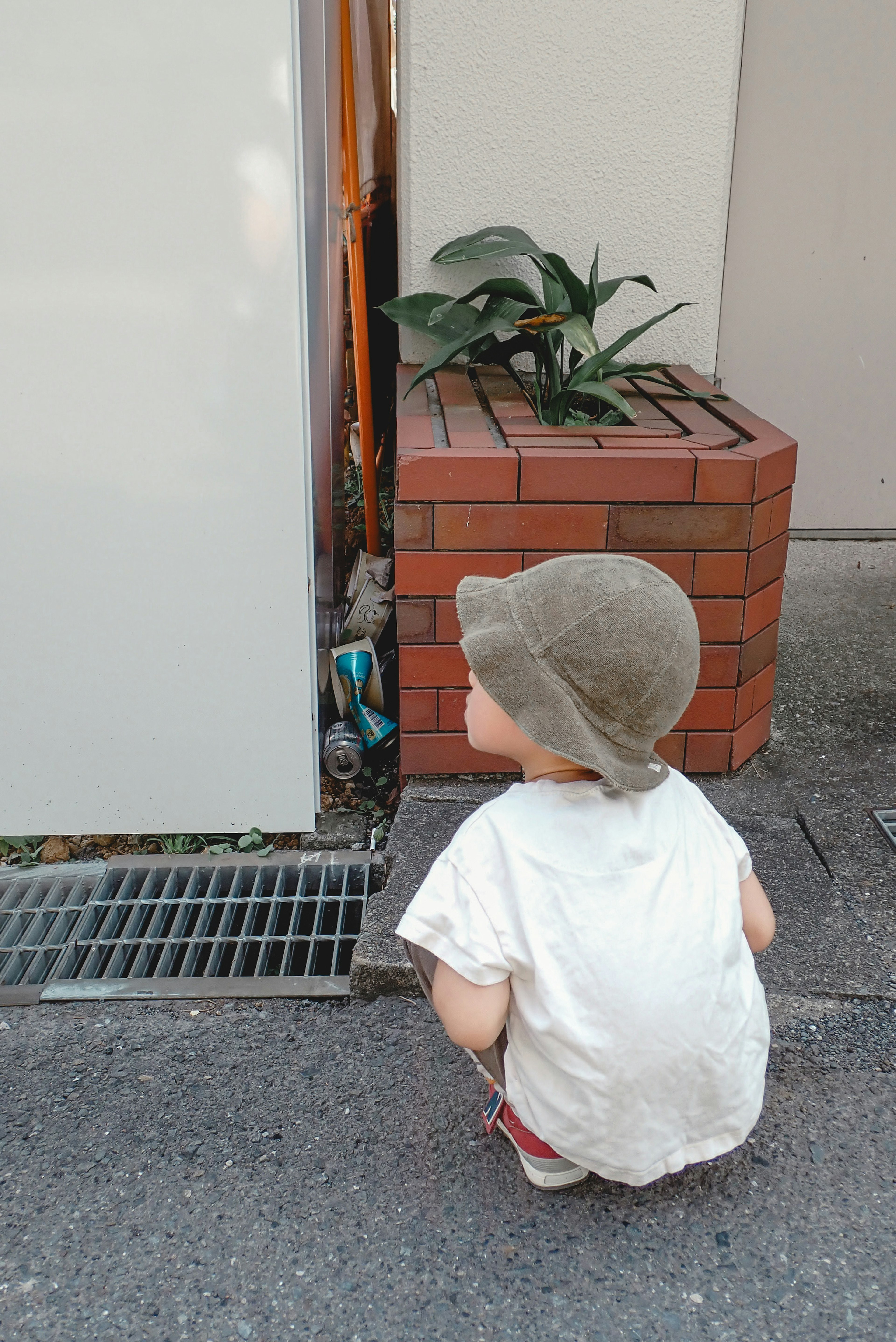 A small child squatting near a planter with plants