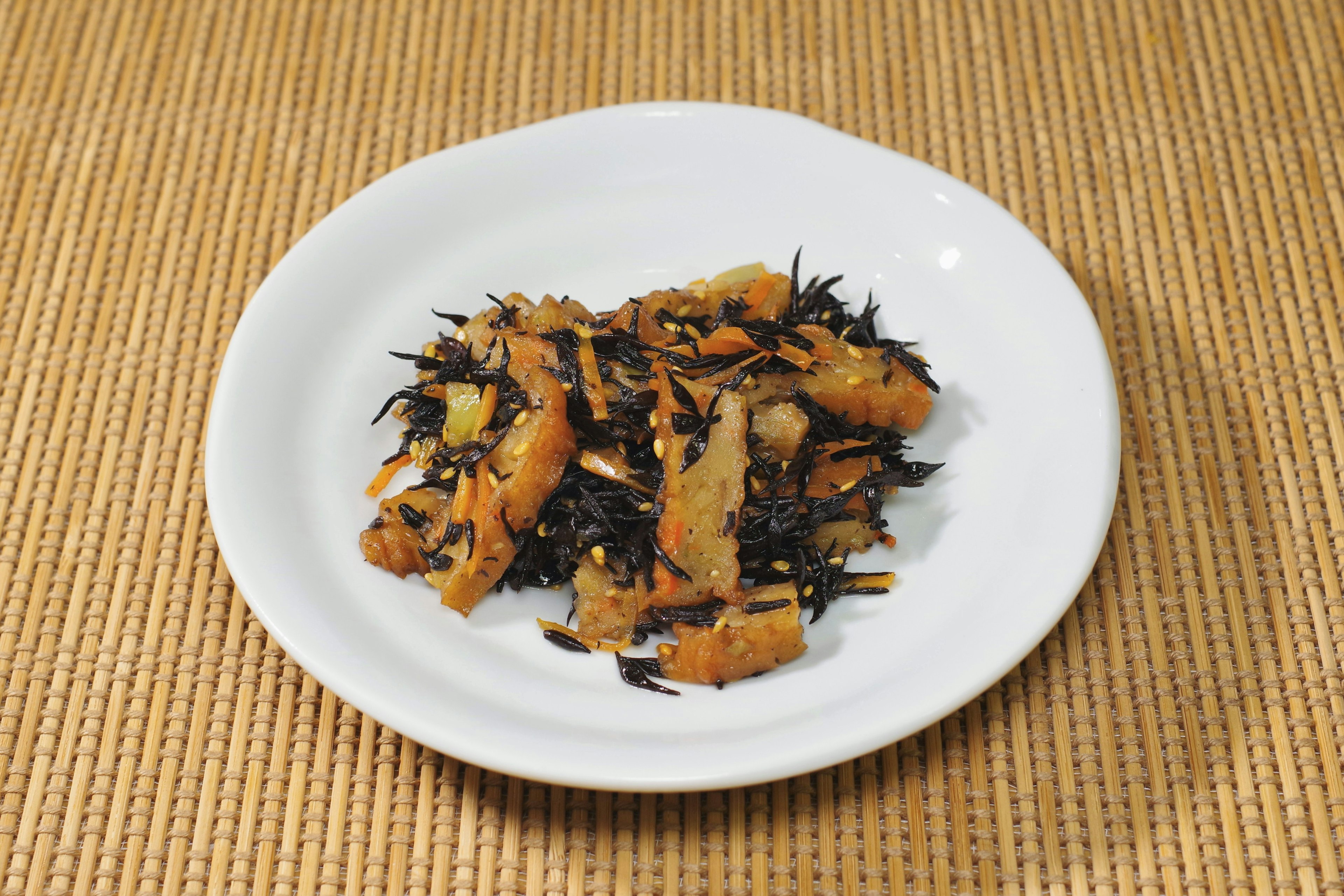 Stir-fried hijiki seaweed with tofu on a white plate