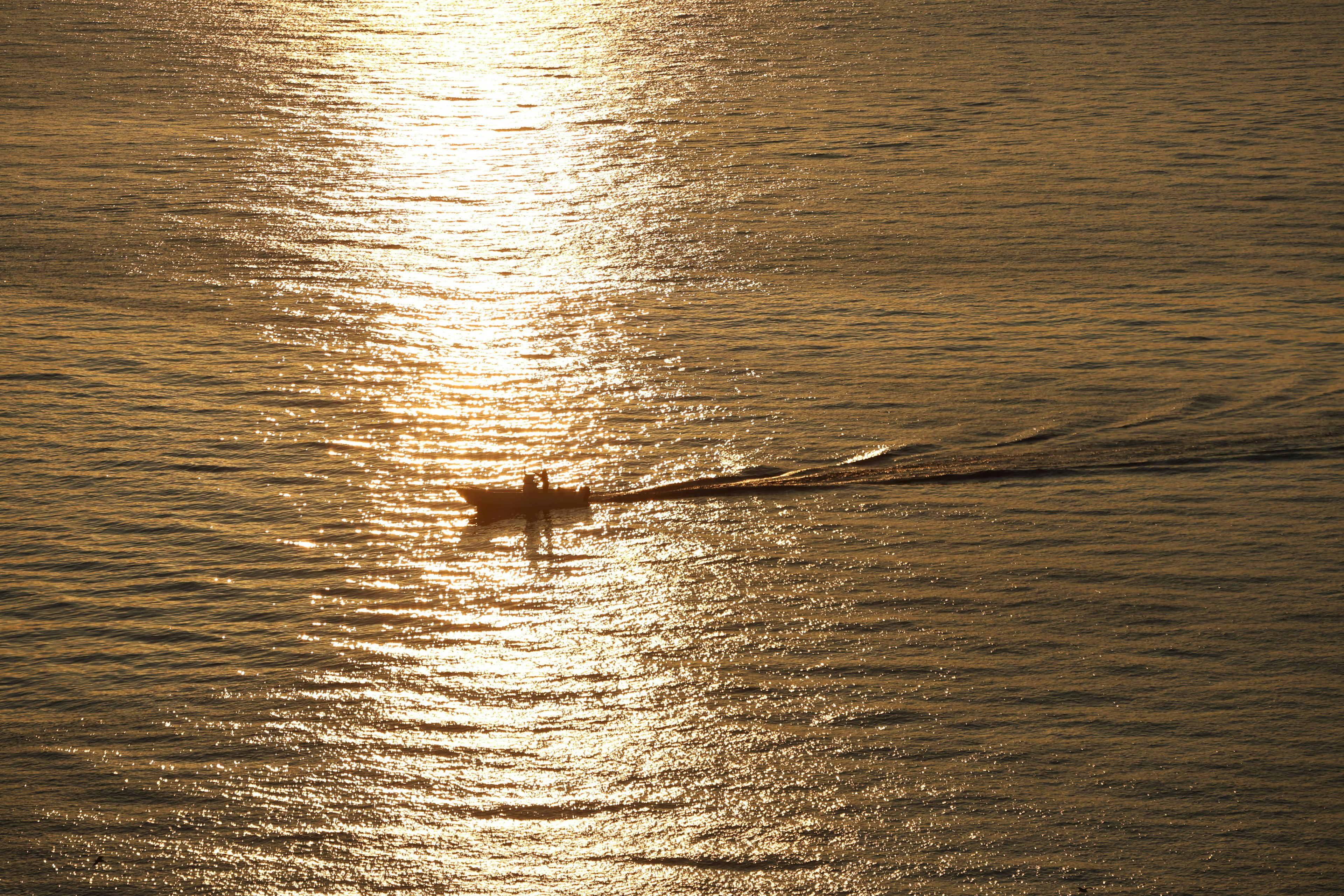 Silhouette eines Bootes, das auf einem goldenen Meer fährt