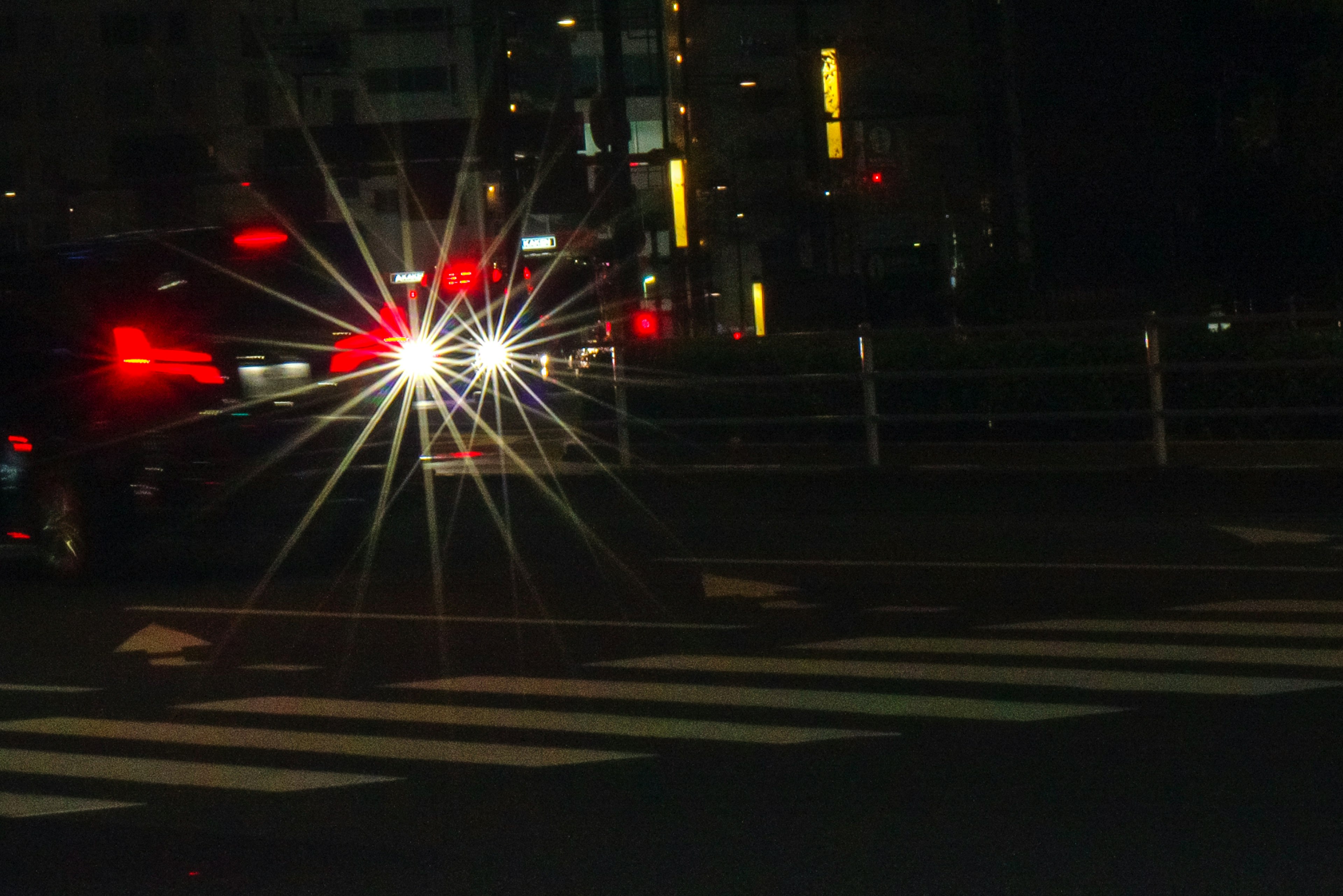 Phares de voiture brillant dans une intersection de ville la nuit avec des lampadaires