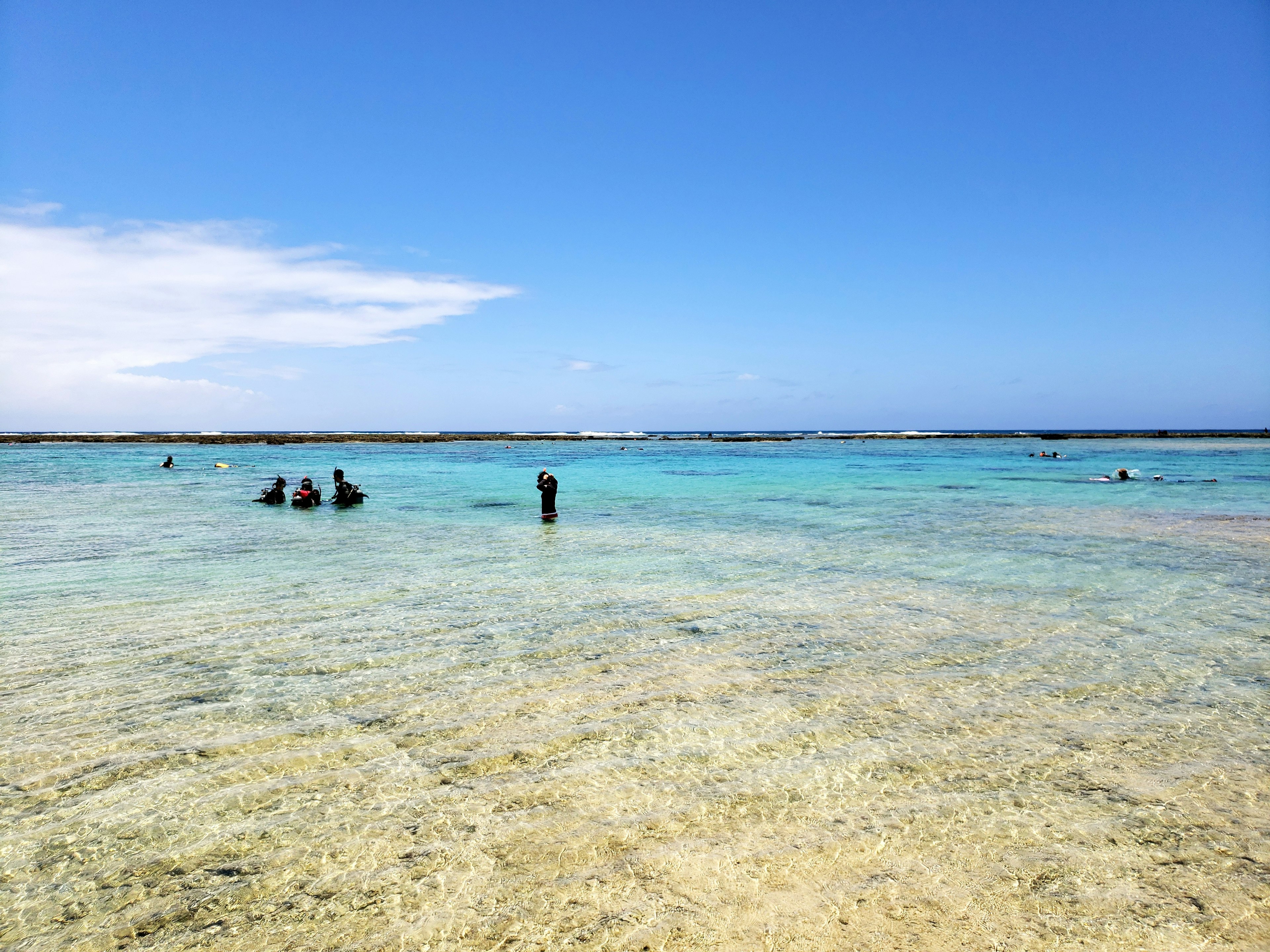 ผู้คนสนุกสนานกับทะเลสีน้ำเงินใสและชายหาดทรายขาว