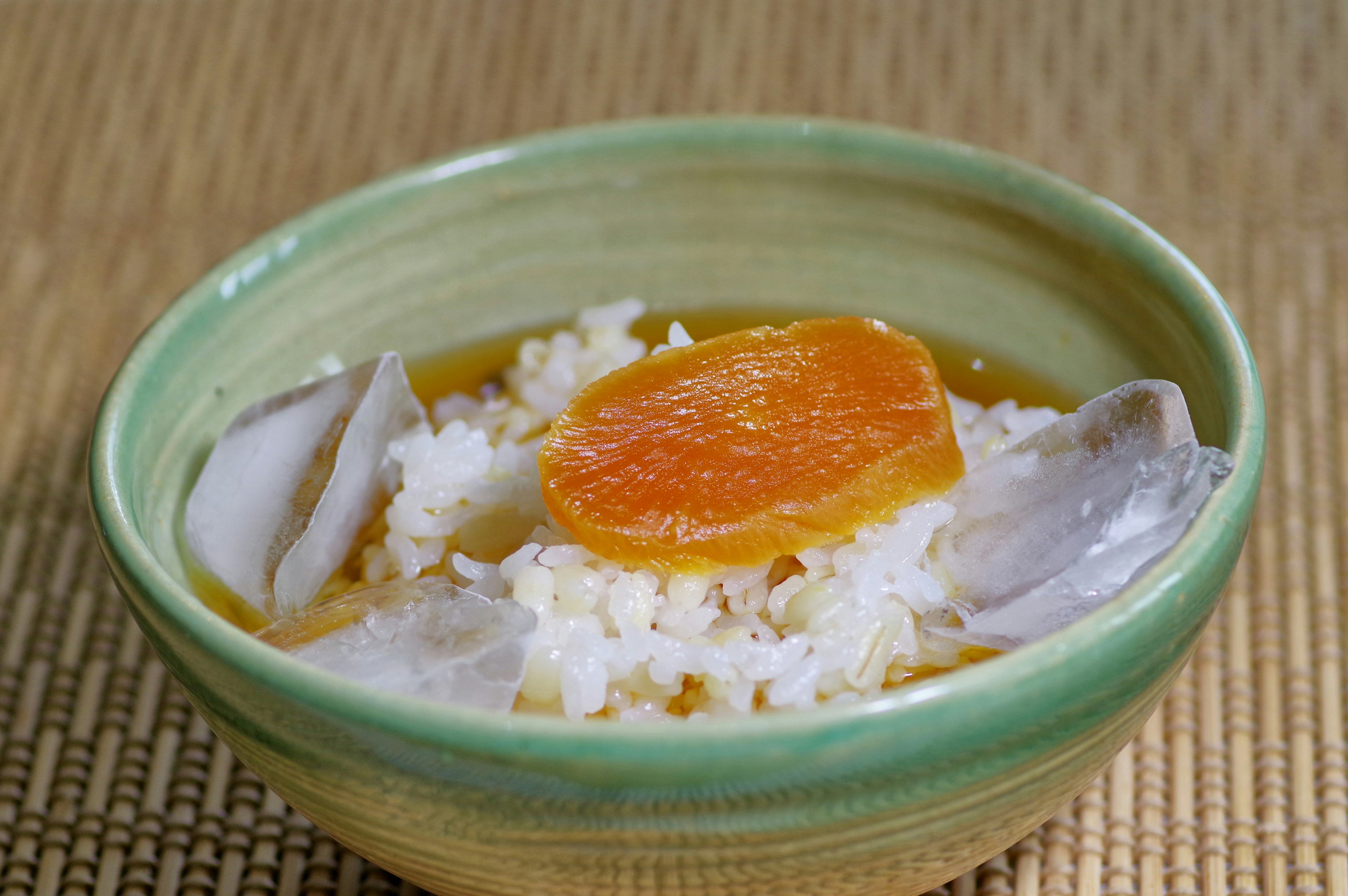 Un bol en céramique verte rempli de riz blanc et de soupe de palourdes garni d'une tranche d'orange