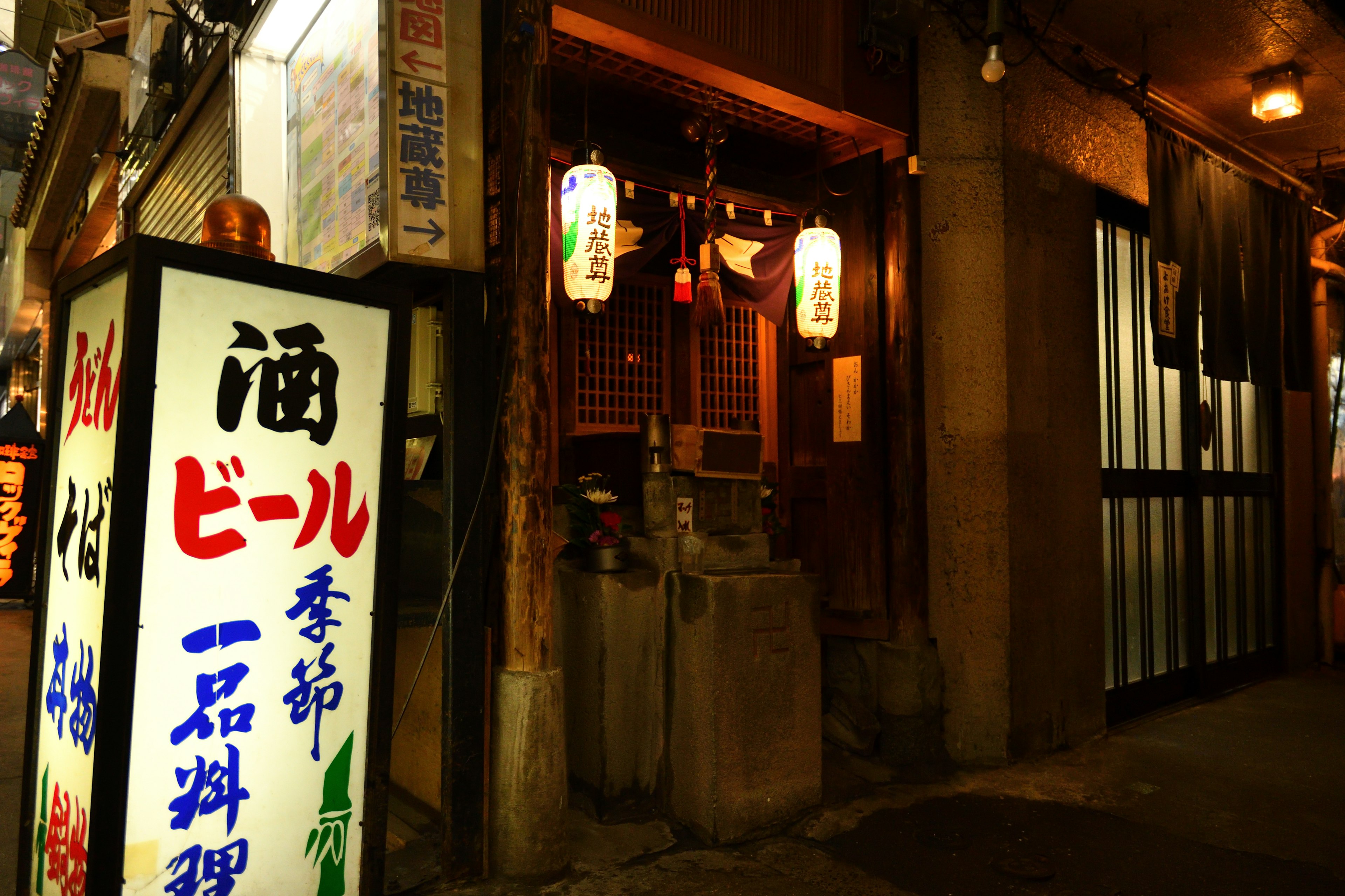 Pintu izakaya dalam pemandangan malam dengan pencahayaan dan tanda khas