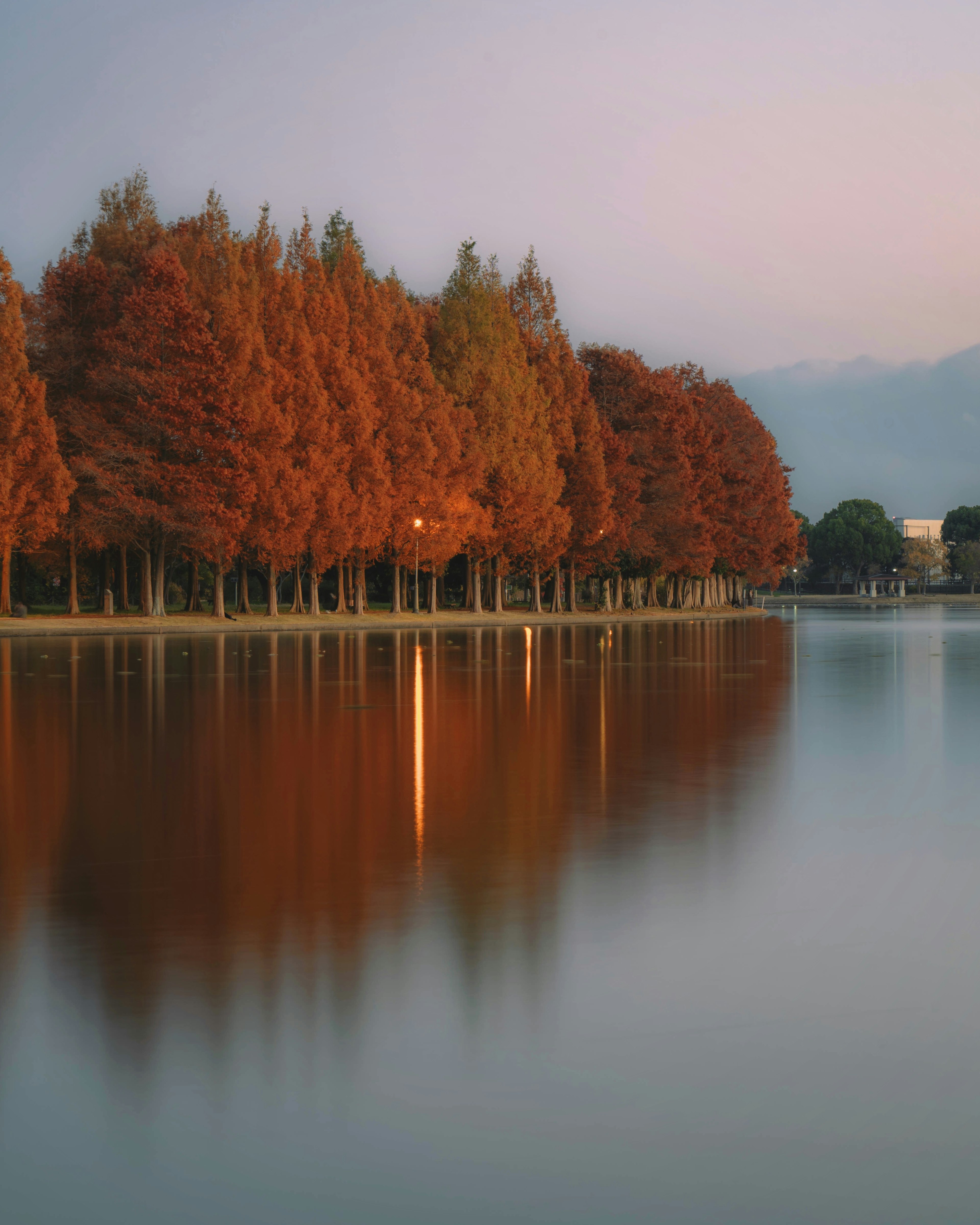 静かな湖の周りに秋の紅葉が映る風景