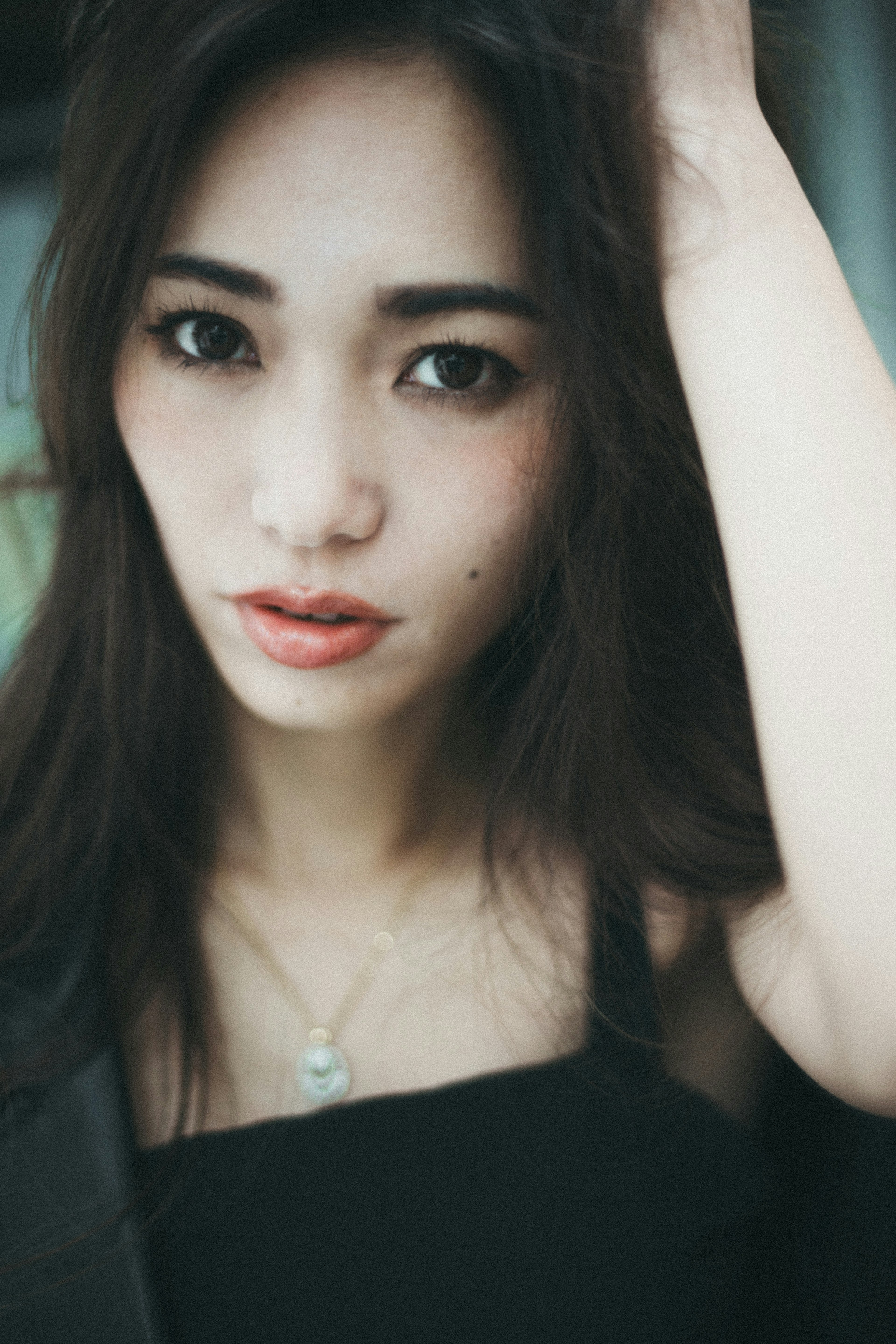 Portrait of a woman in black clothing touching her hair Soft lighting creates a gentle atmosphere