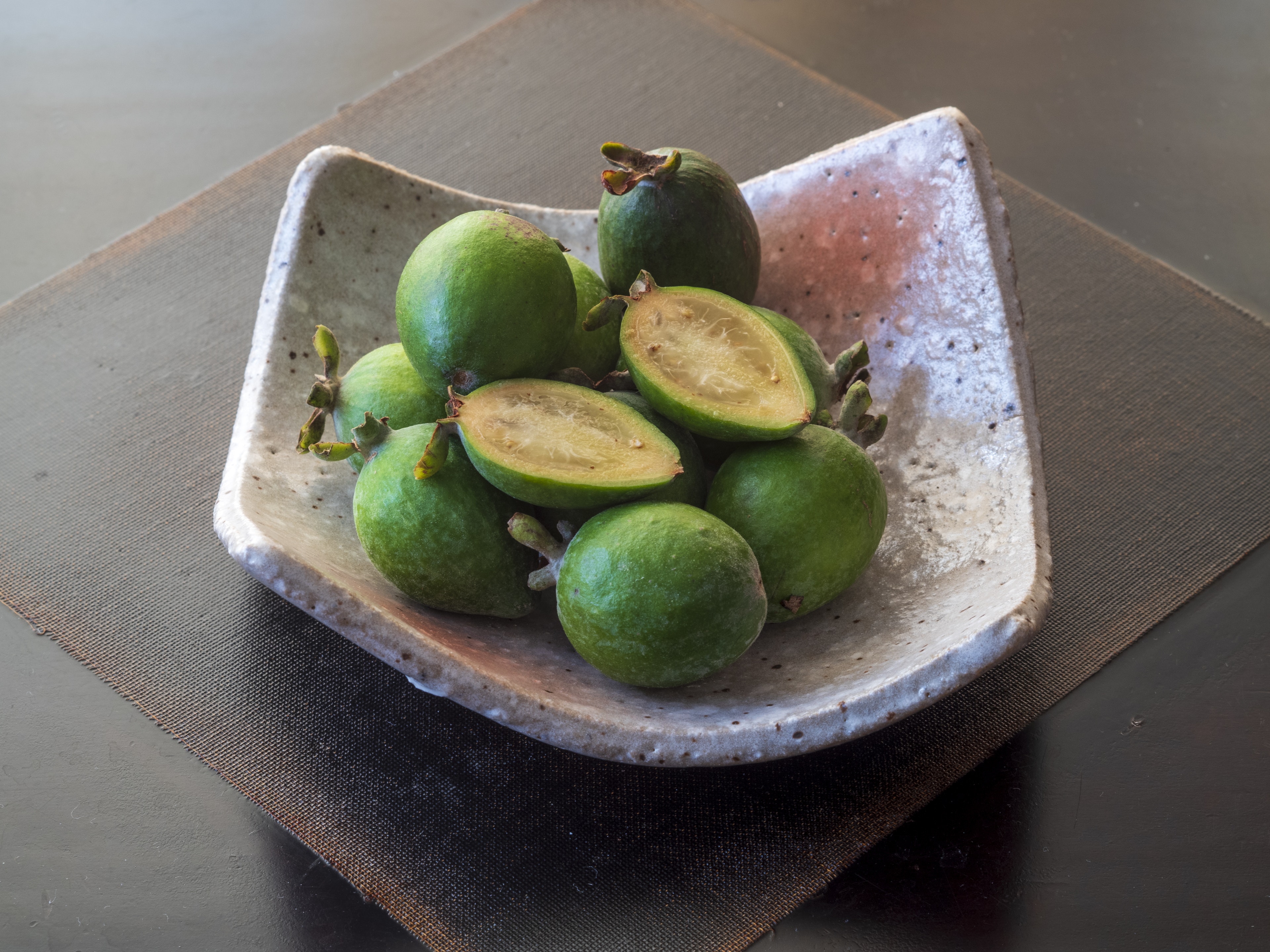 Un plat blanc rempli de fruits verts et de morceaux tranchés