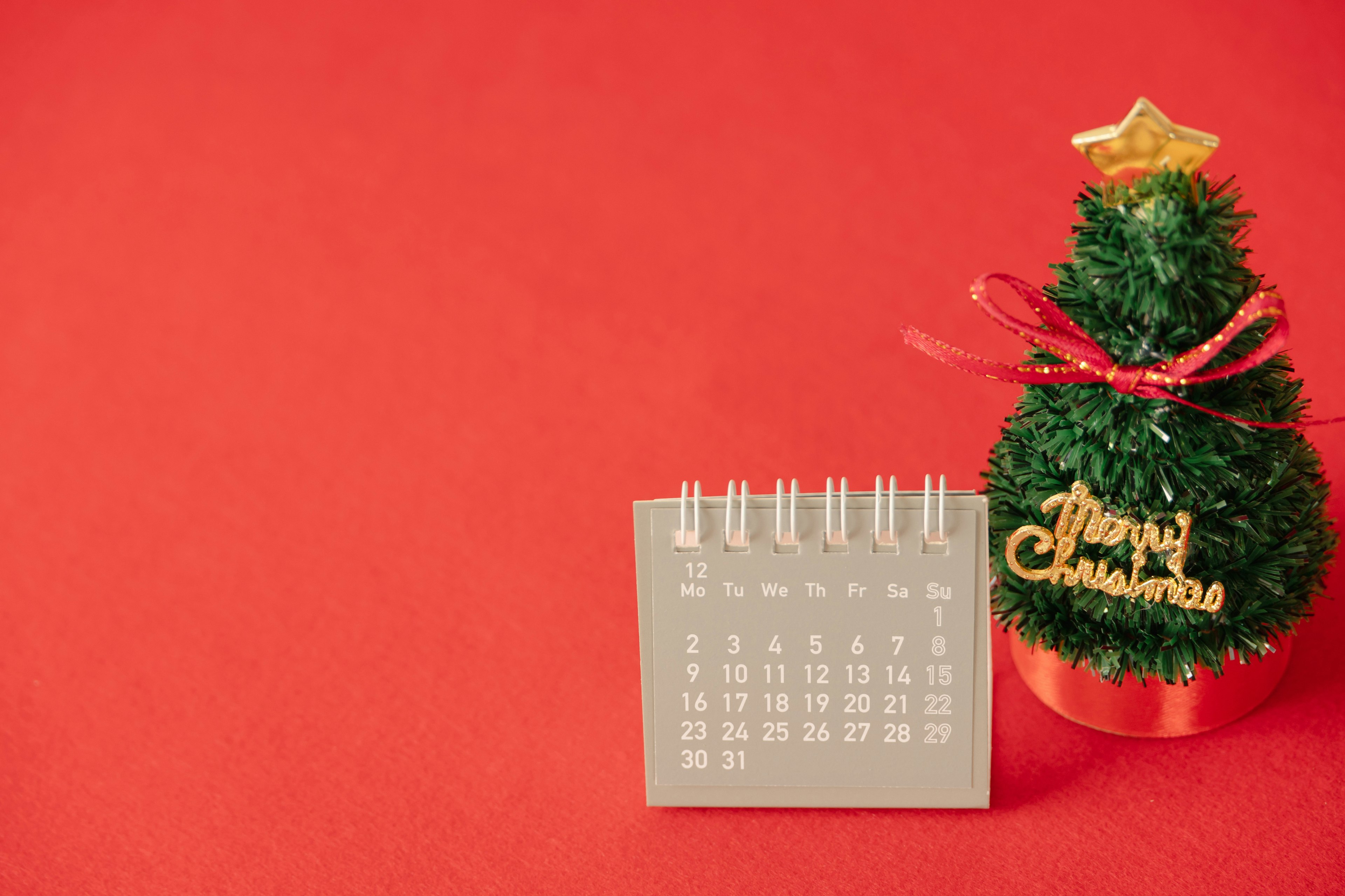 Un pequeño árbol de Navidad y un calendario sobre un fondo rojo