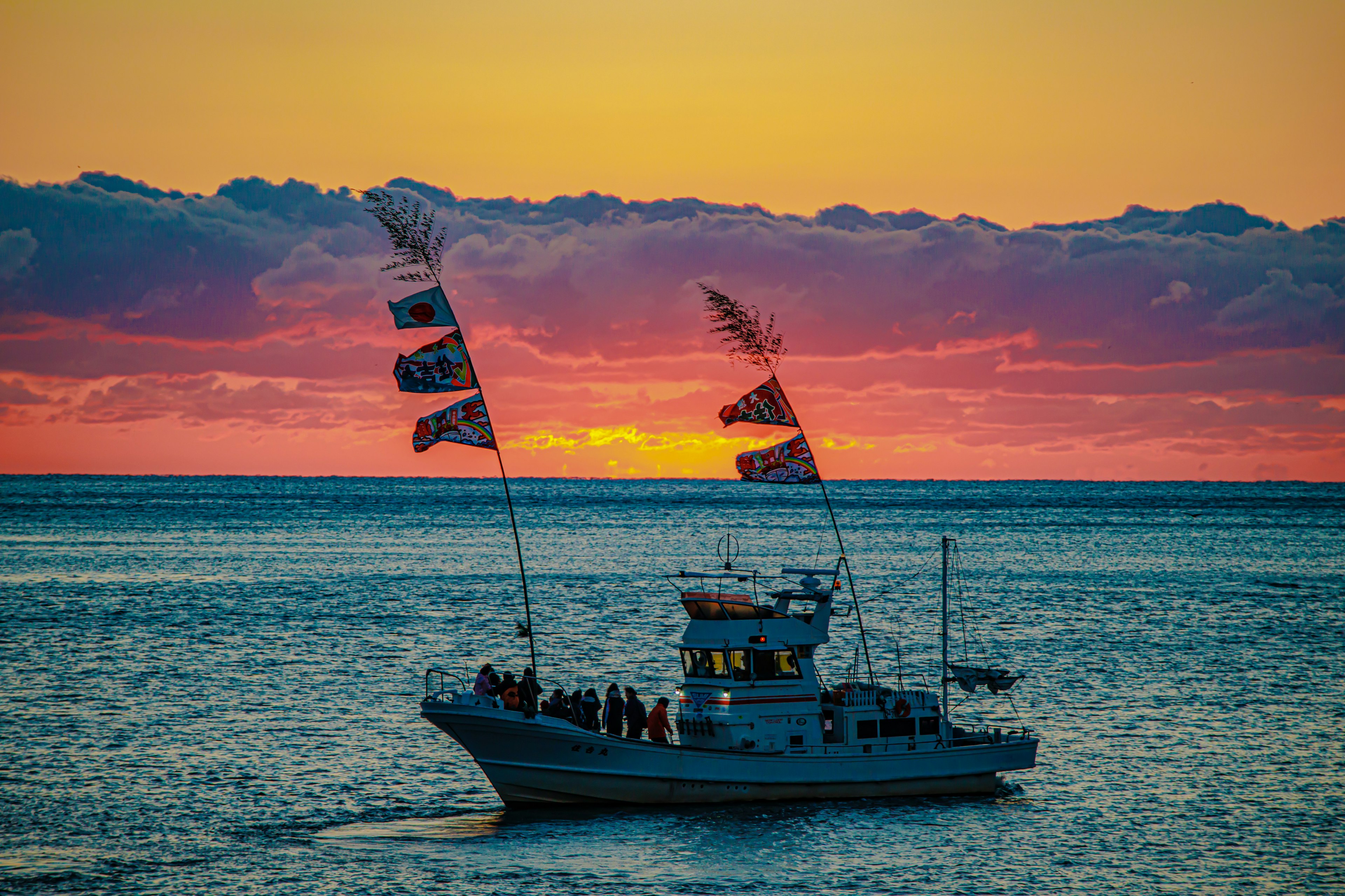 A beautiful scene of a boat with flags floating on the sunset sea