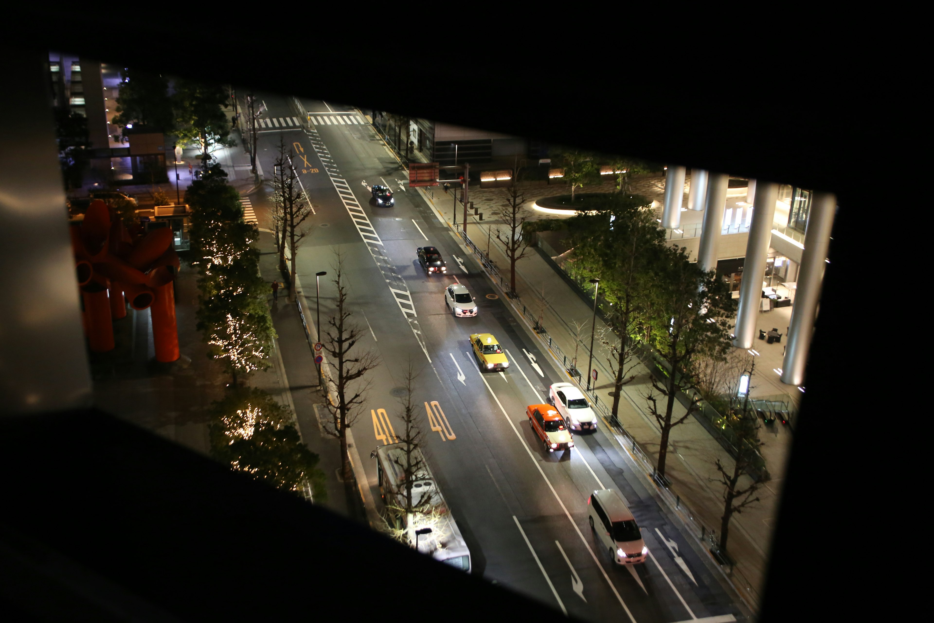 夜の街並みを見下ろす窓からの眺め 車が通る通りと街灯が映る