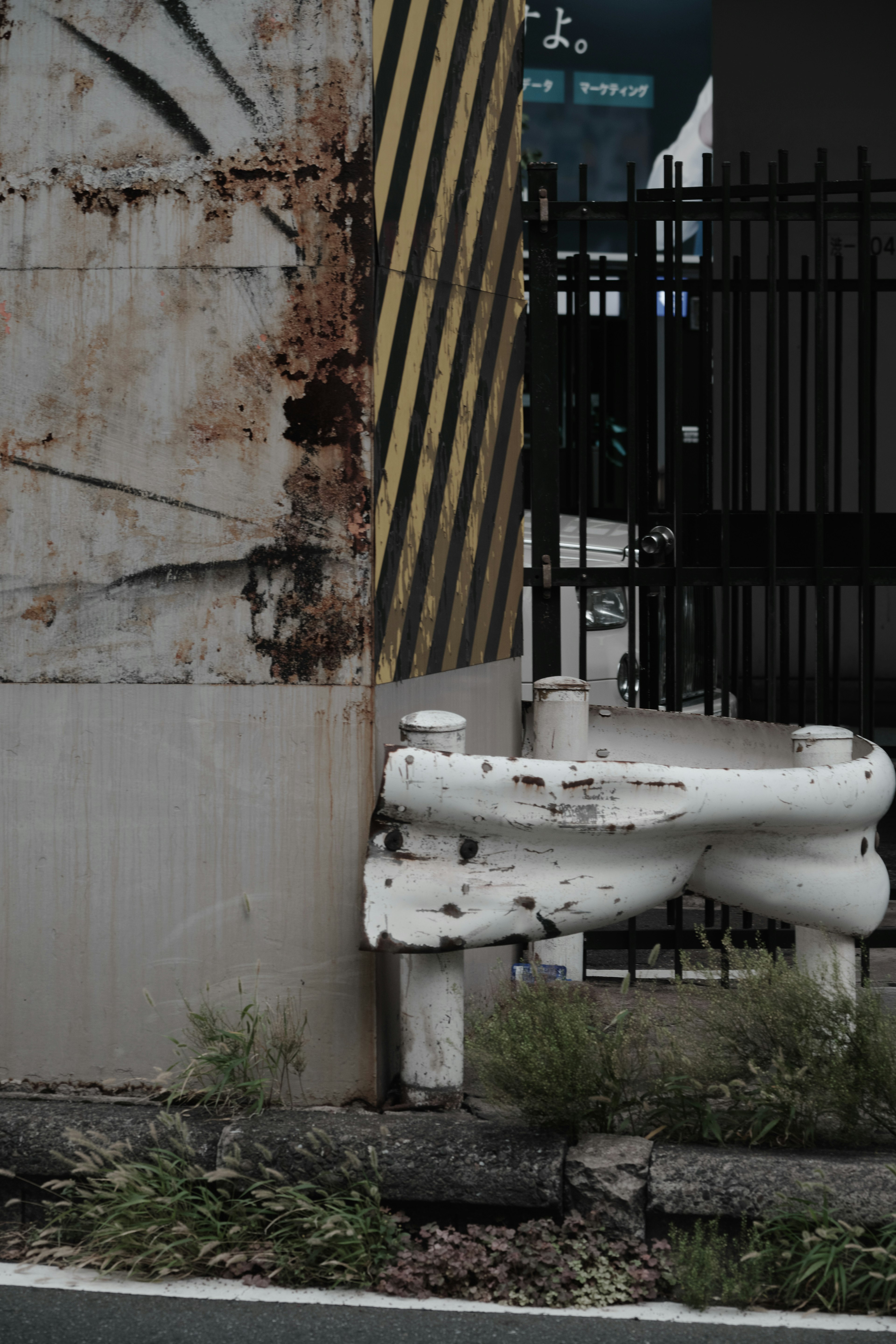 L'image présente un mur rouillé avec des rayures jaunes et noires et une structure blanche