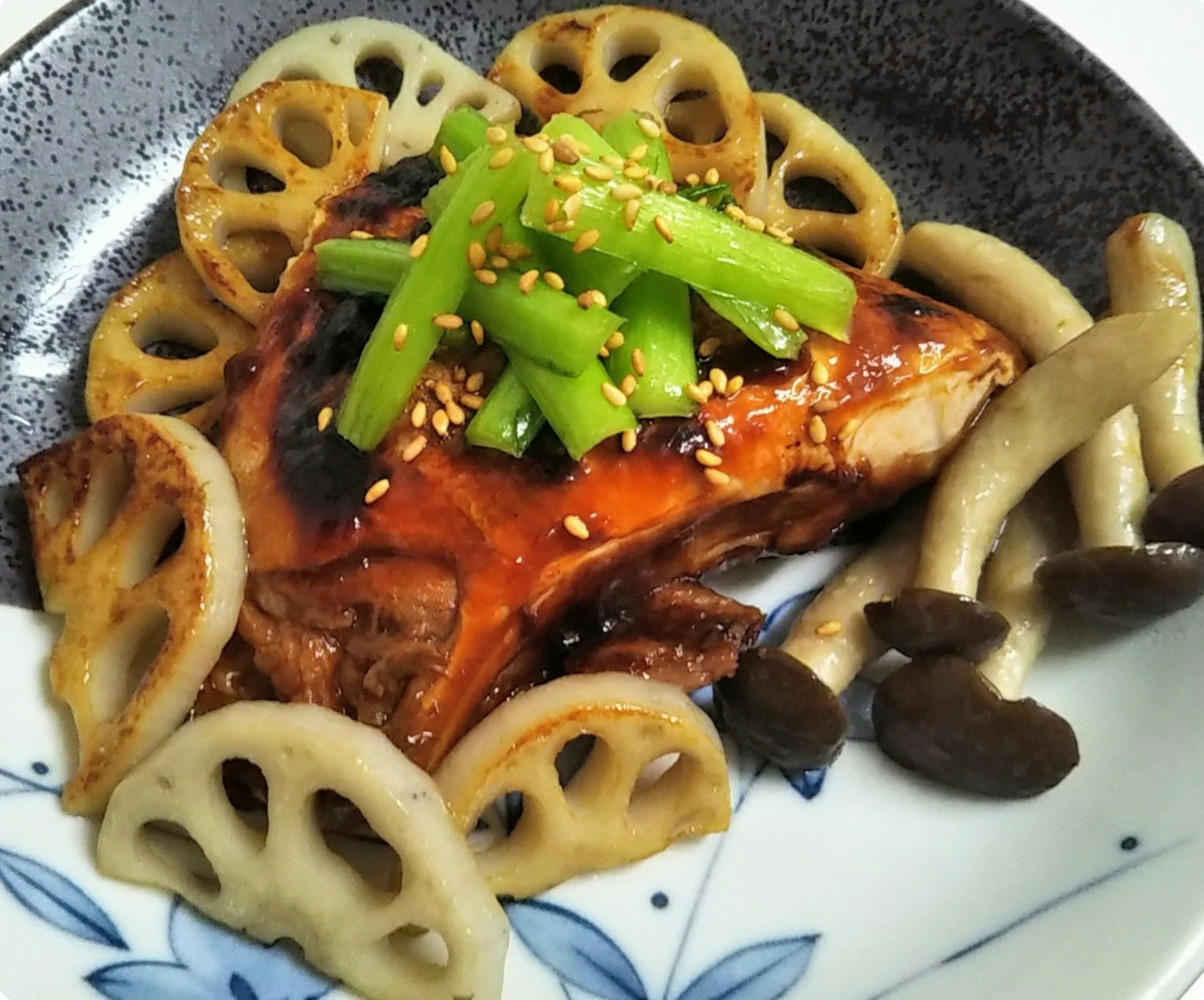 Plat avec du poulet et des racines de lotus garni d'oignons verts et de sésame