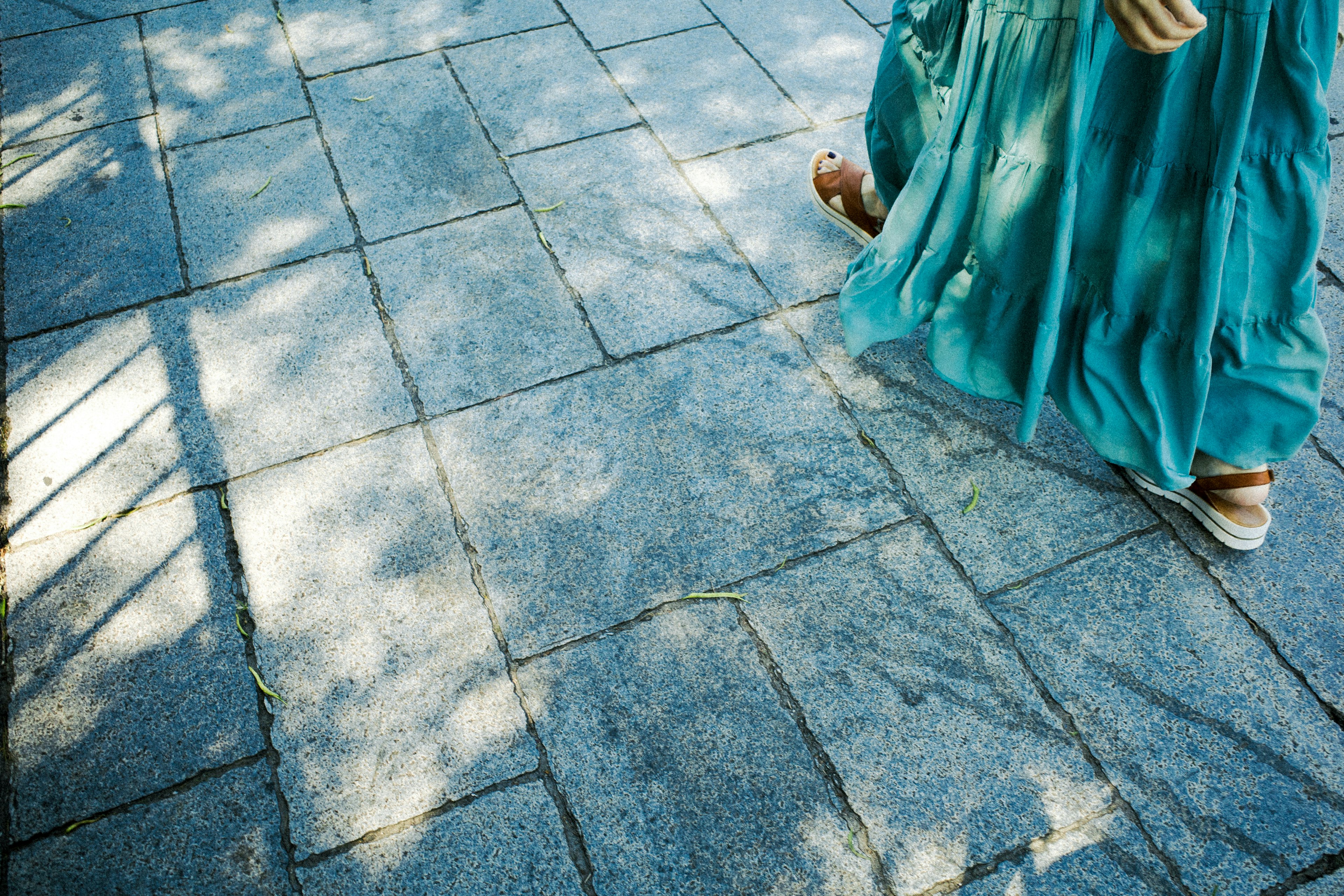 Una persona con un vestido azul caminando sobre un pavimento de piedra