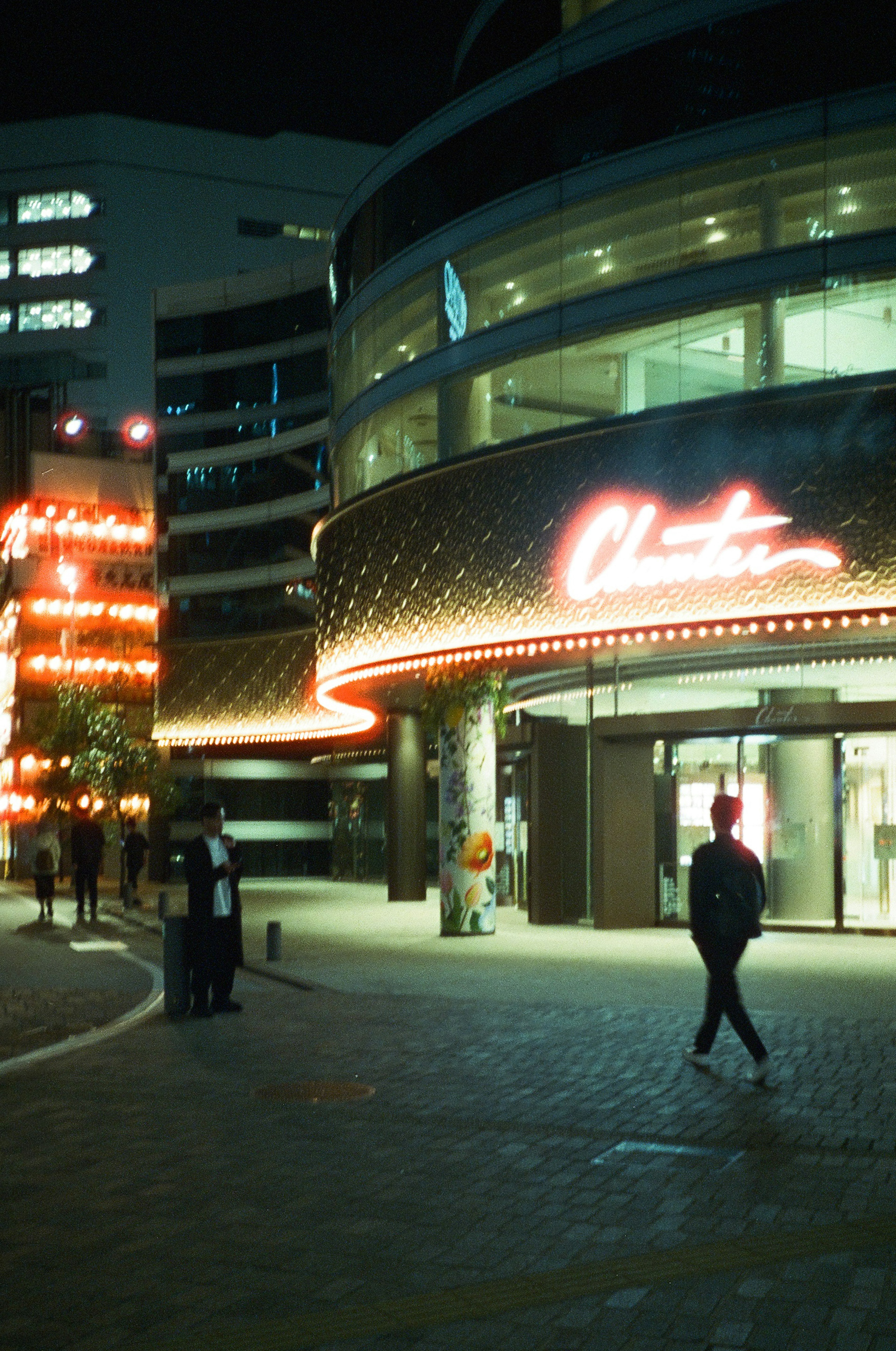 Illuminated entrance of a building at night with a passerby