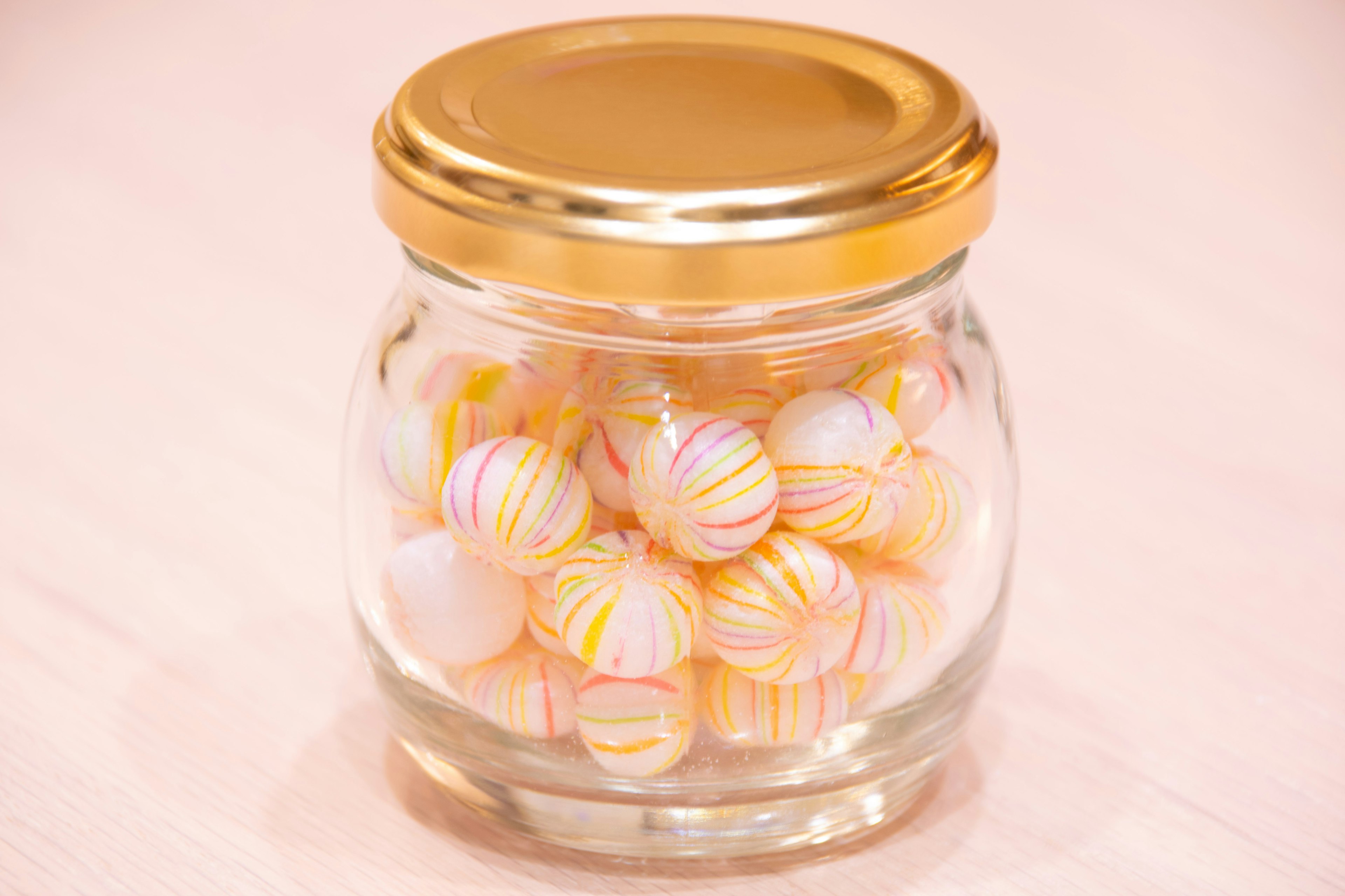 Glass jar filled with white and orange striped beads