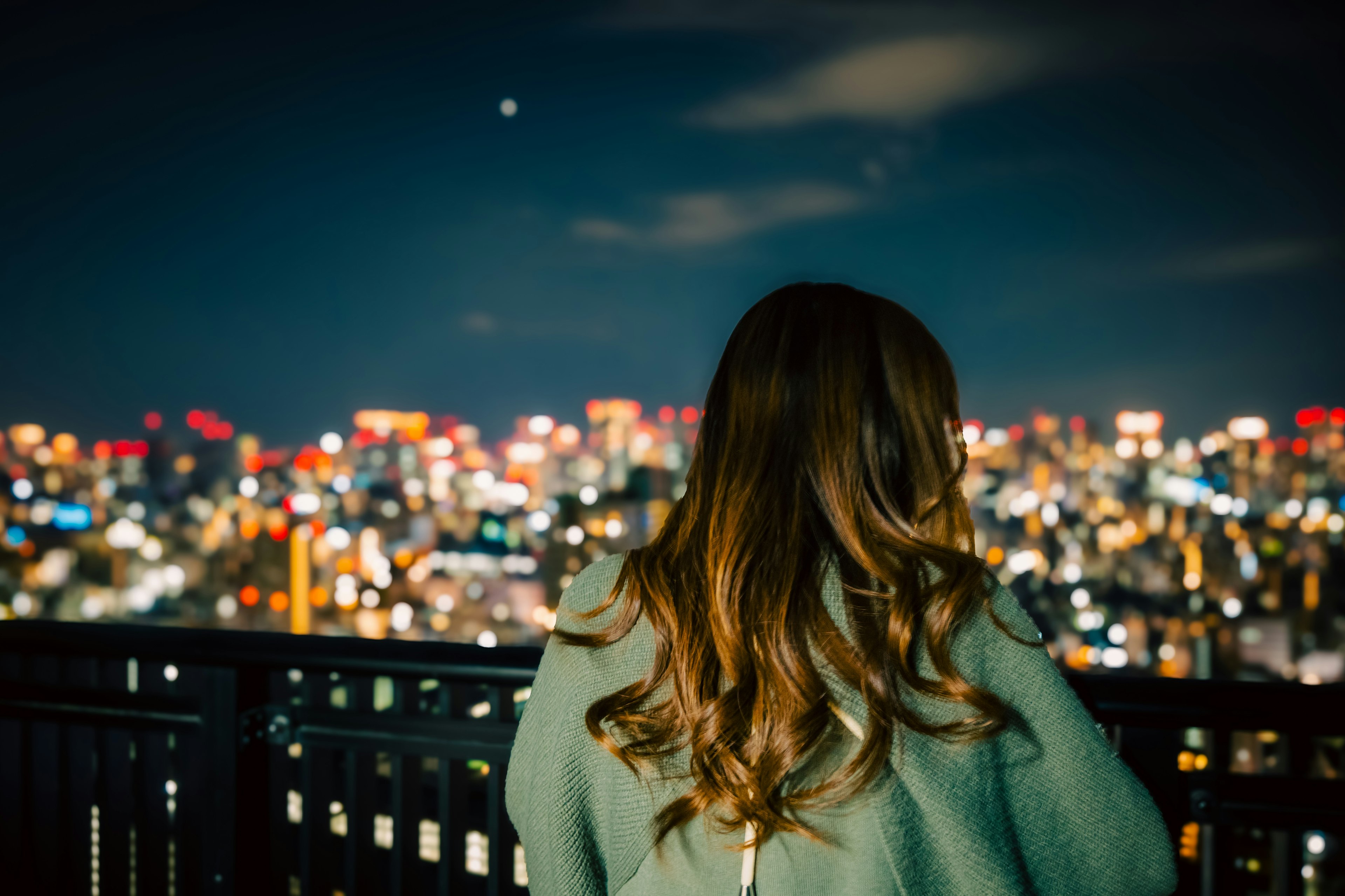 Mujer mirando el horizonte de la ciudad por la noche con luces vibrantes