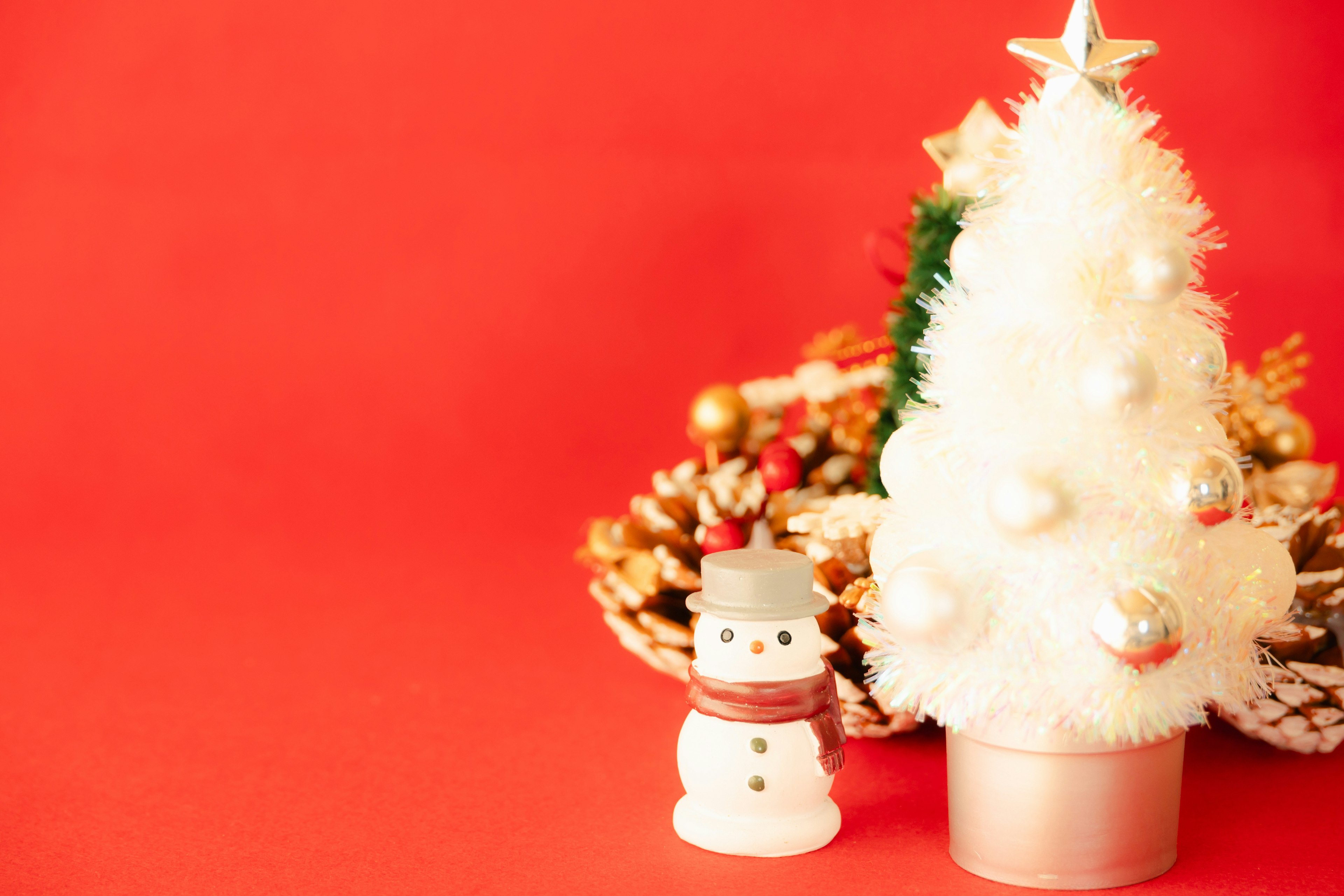 A white Christmas tree and a snowman on a red background