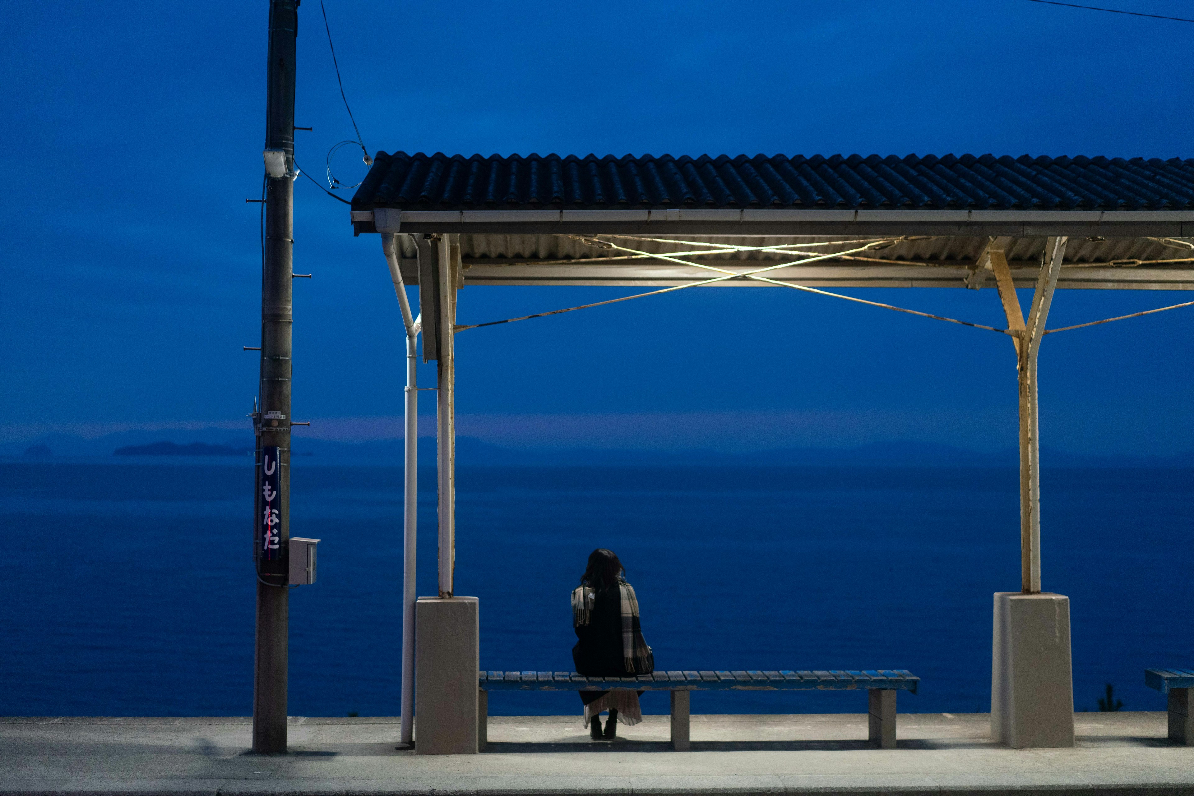 Une personne attendant sur un banc sous un ciel bleu à une gare