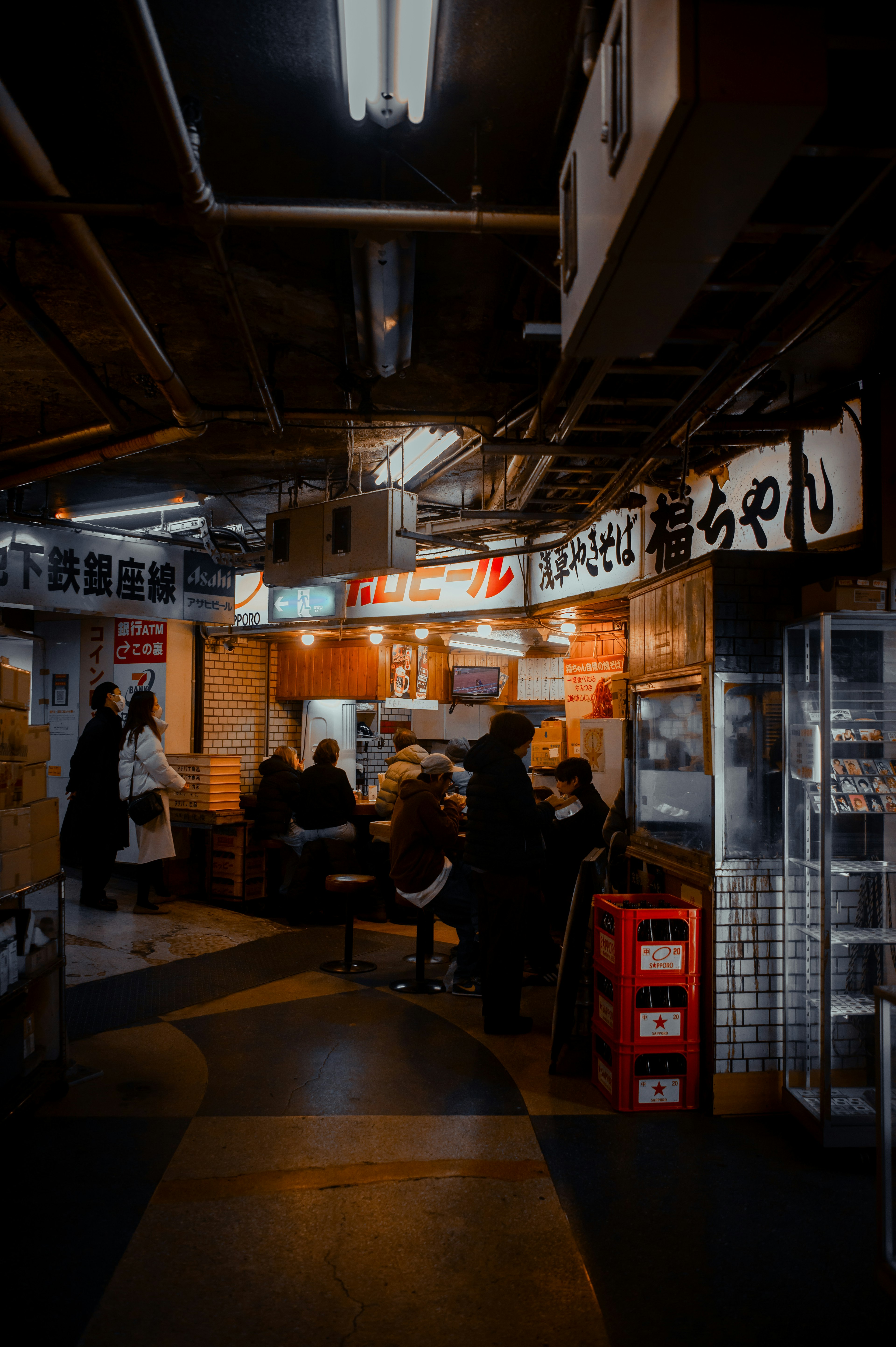 People gathering in a dimly lit indoor food alley