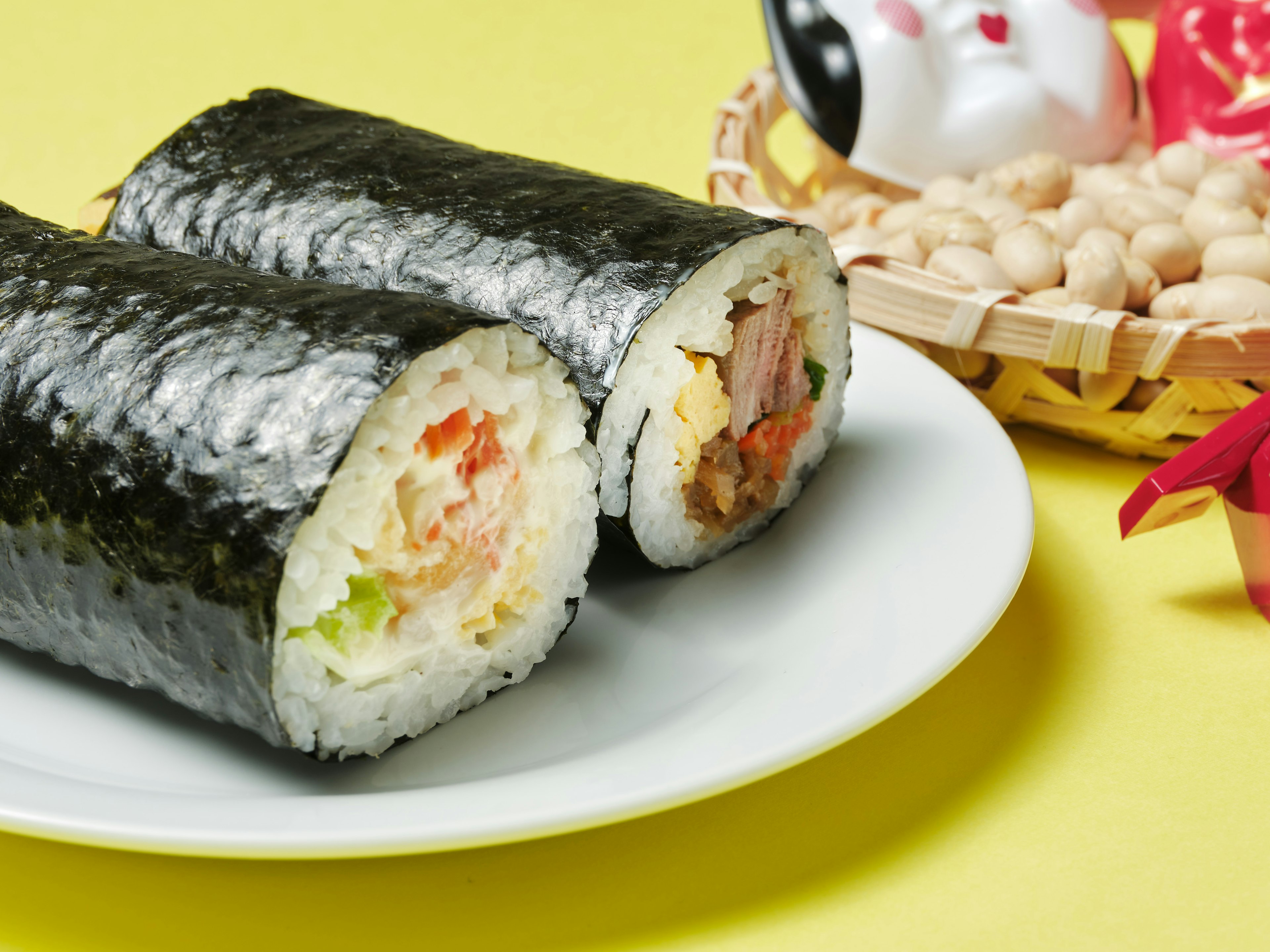 Cuộn sushi trên đĩa trắng với nền vàng và các yếu tố trang trí