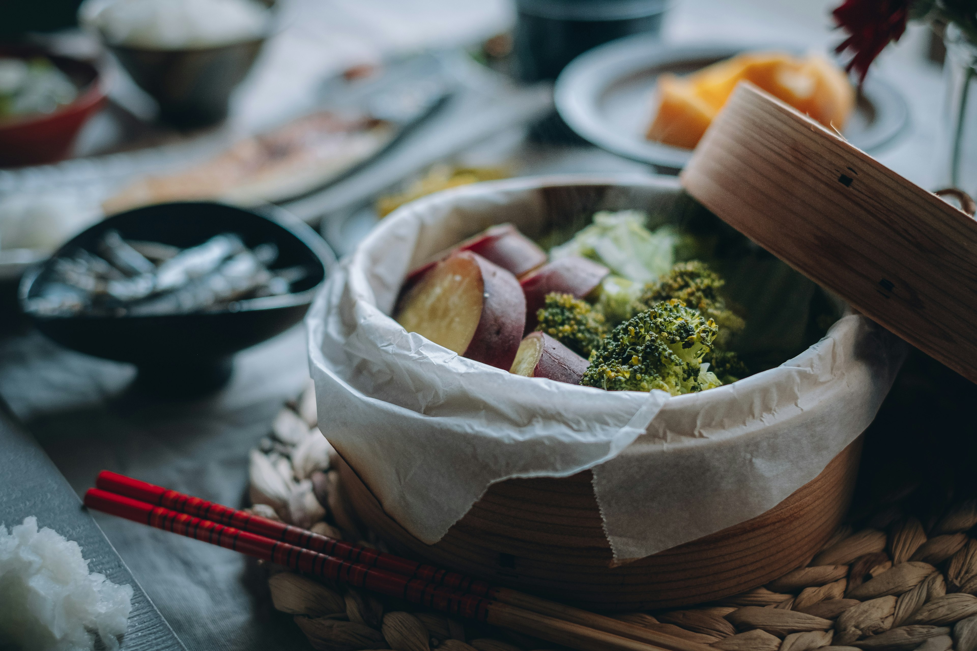 Broccoli e patate dolci cotti a vapore in un cestello di bambù su un tavolo