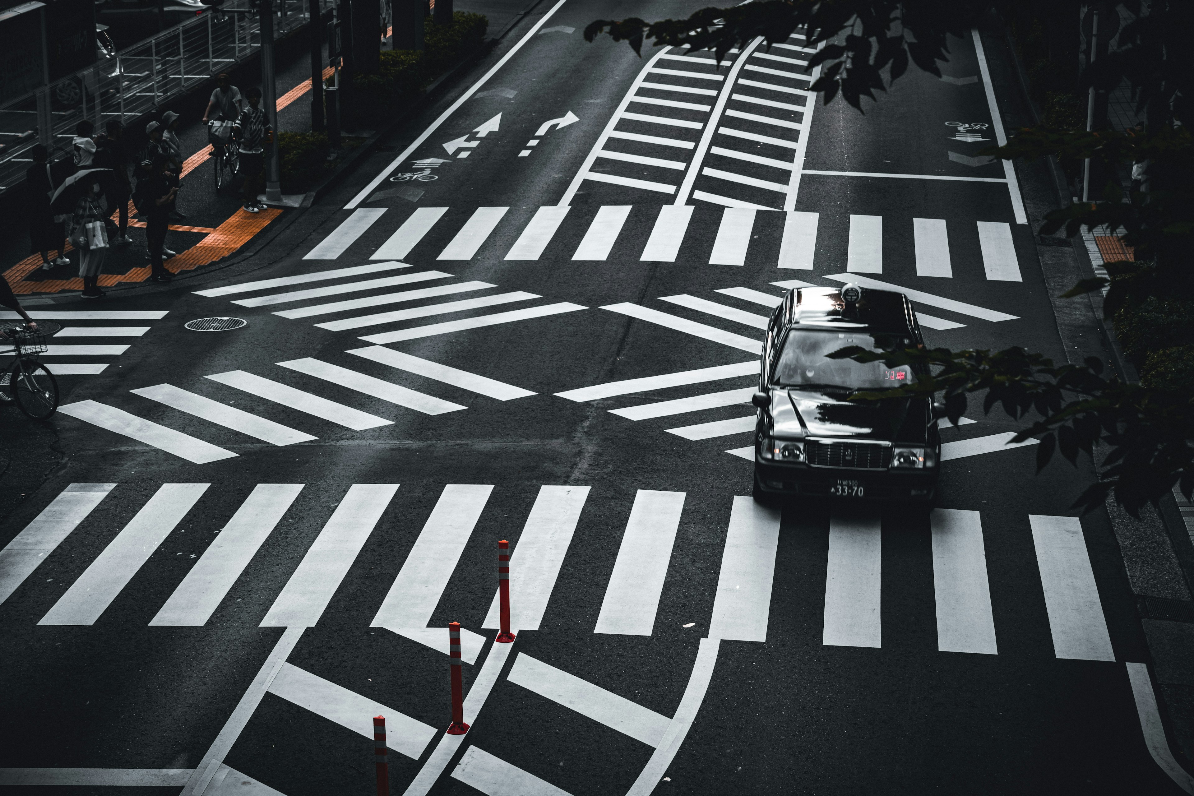 Un coche que pasa por una intersección urbana con pasos de cebra en blanco y negro