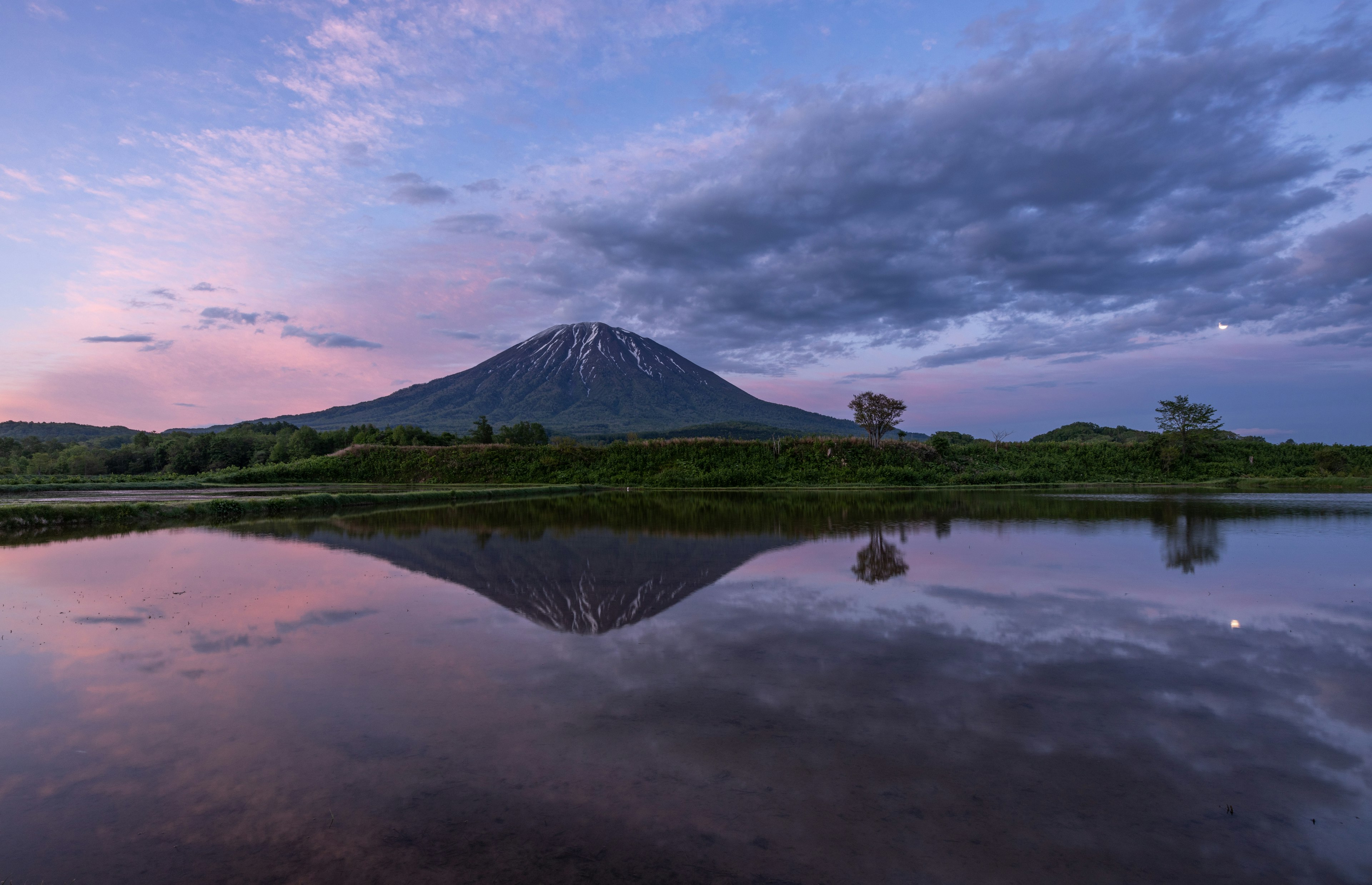 Vista escénica de una montaña reflejada en el agua durante el crepúsculo