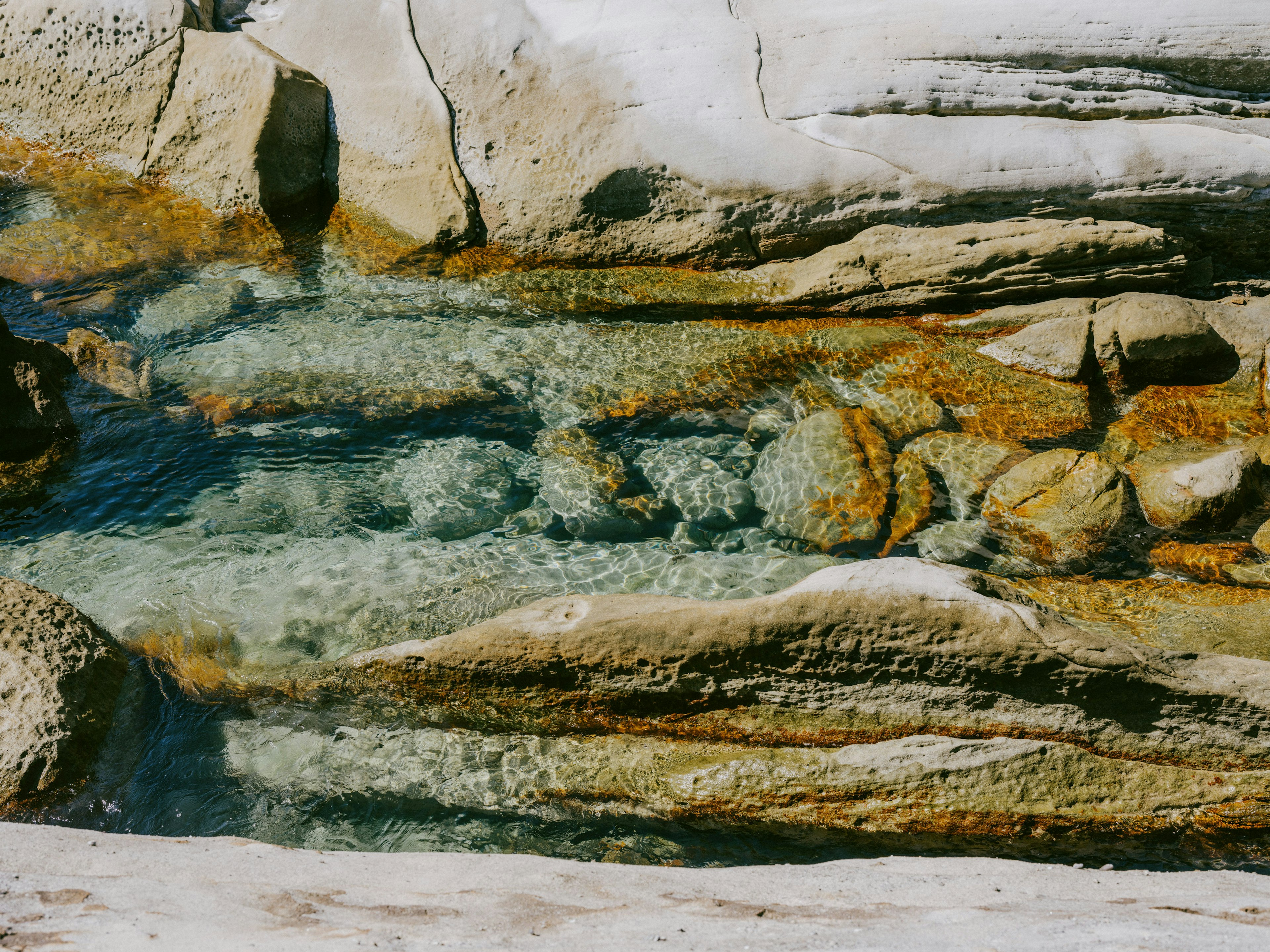 Ruscello chiaro che scorre su pietre colorate e rocce