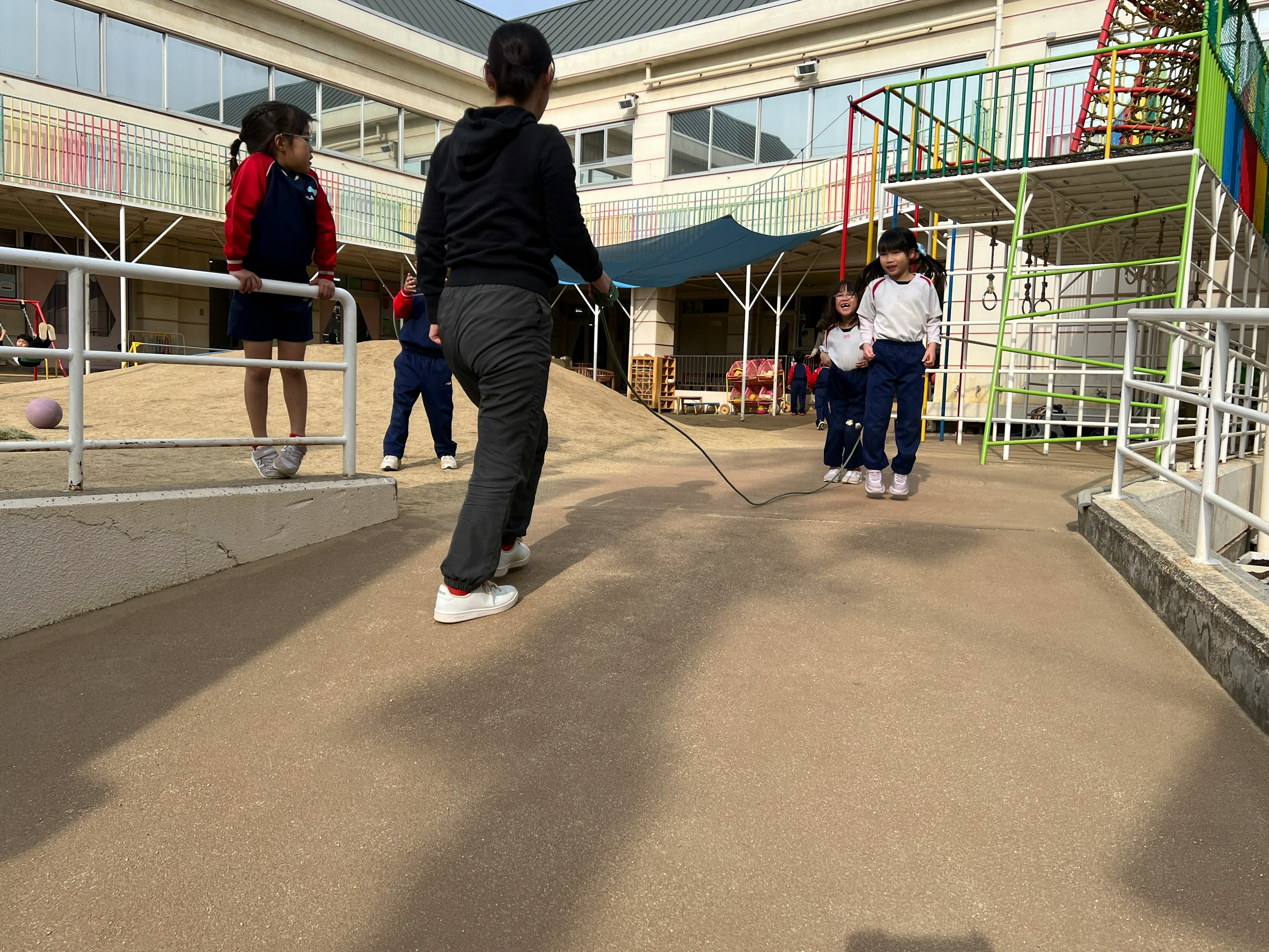 Kinder spielen auf einem Schulspielplatz mit einer Rutsche und einer Kletterstruktur