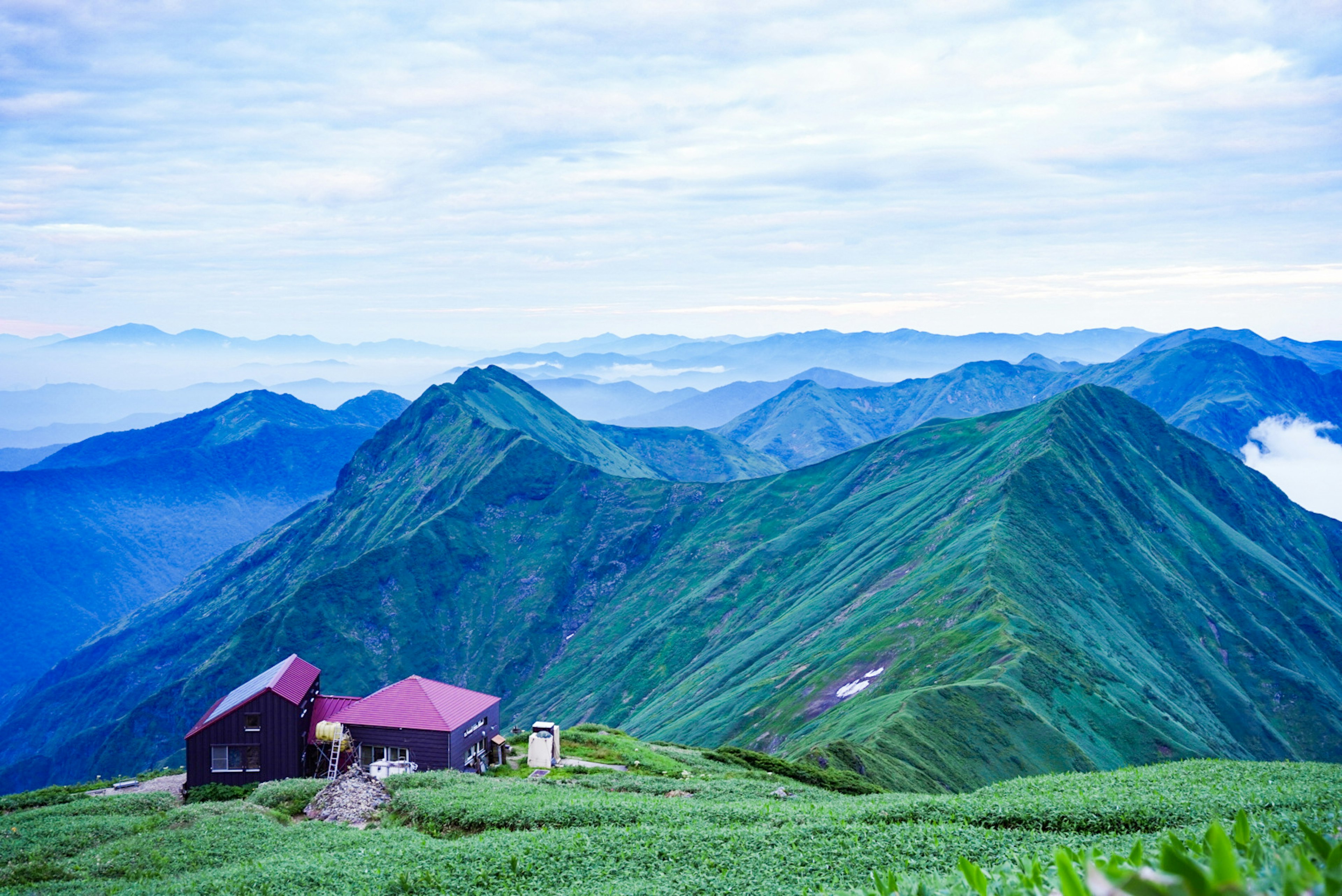 山々に囲まれた小屋と緑の風景