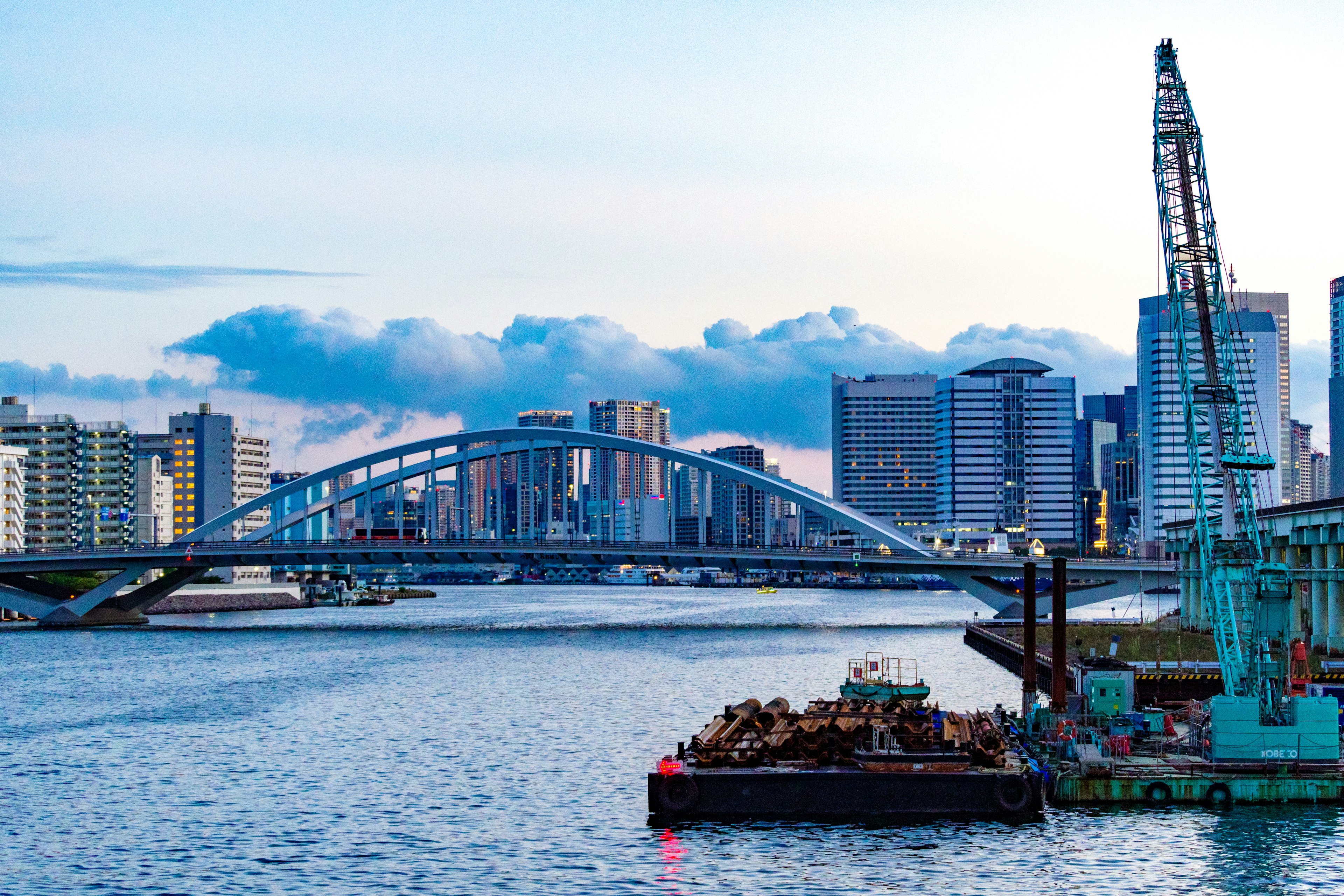 Scenic view of an arch bridge over water with modern buildings in the background