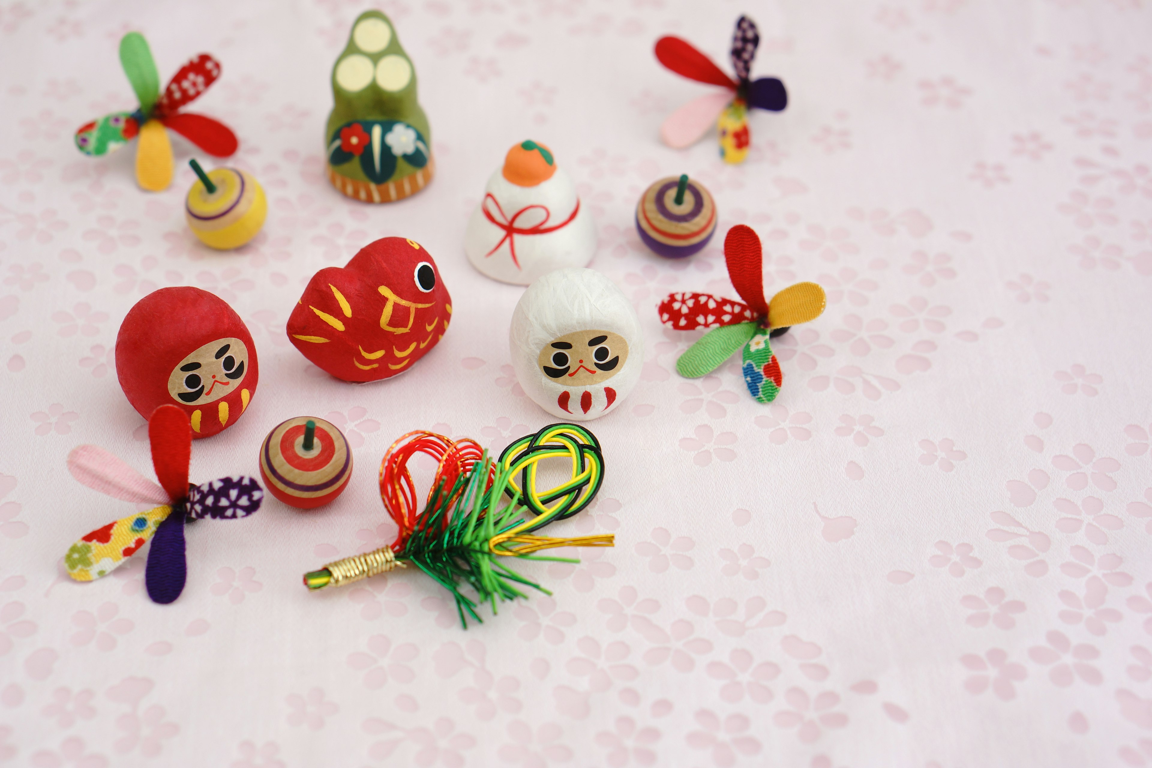 Colorful traditional Japanese toys and ornaments arranged on a pink background