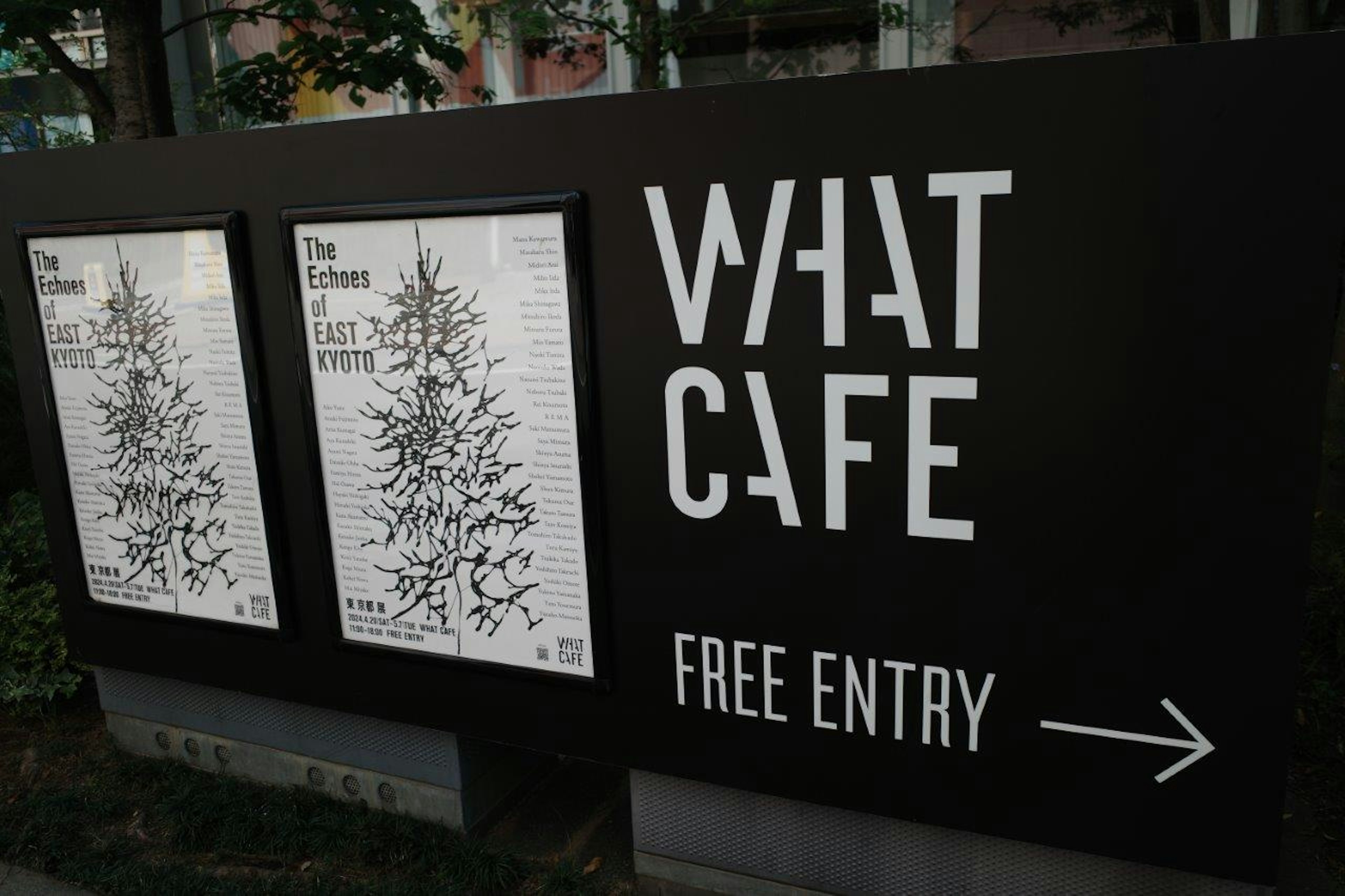 標牌上寫著'WHAT CAFE'和'免費入場'及箭頭